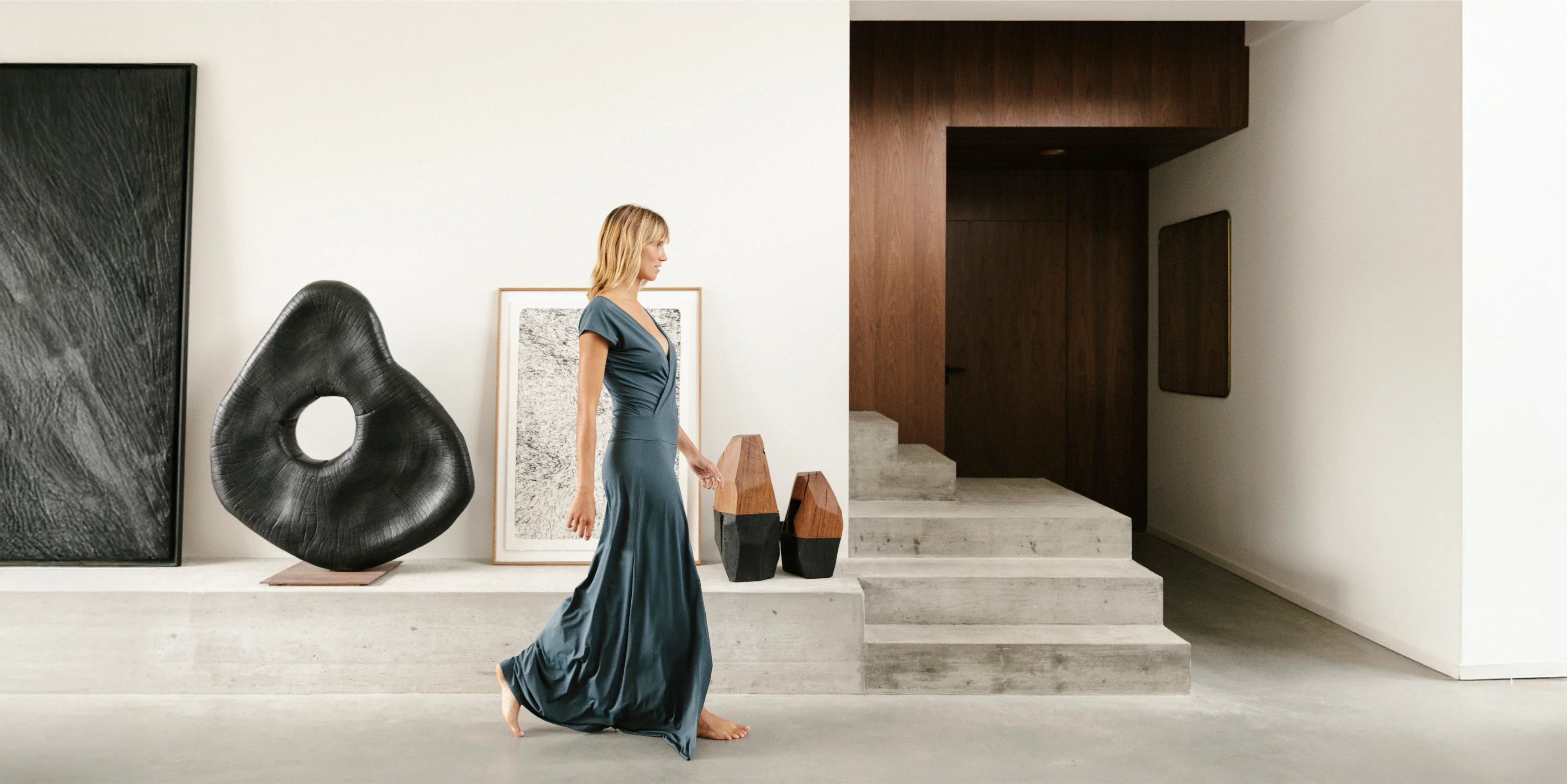 Frau mit grauem Kleid läuft durch einen Hausflur