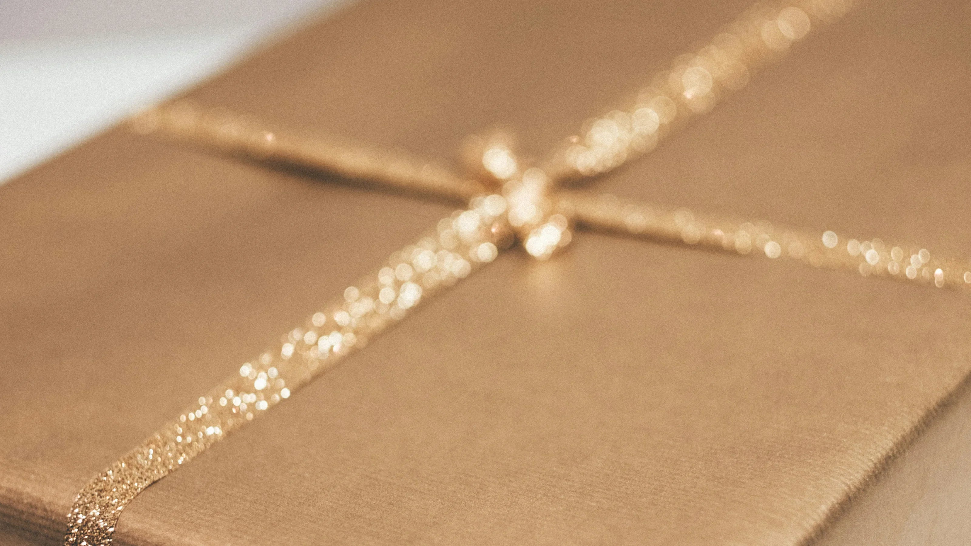 Nahaufnahme eines goldfarben verpackten Geschenks mit glitzernder Schleife.