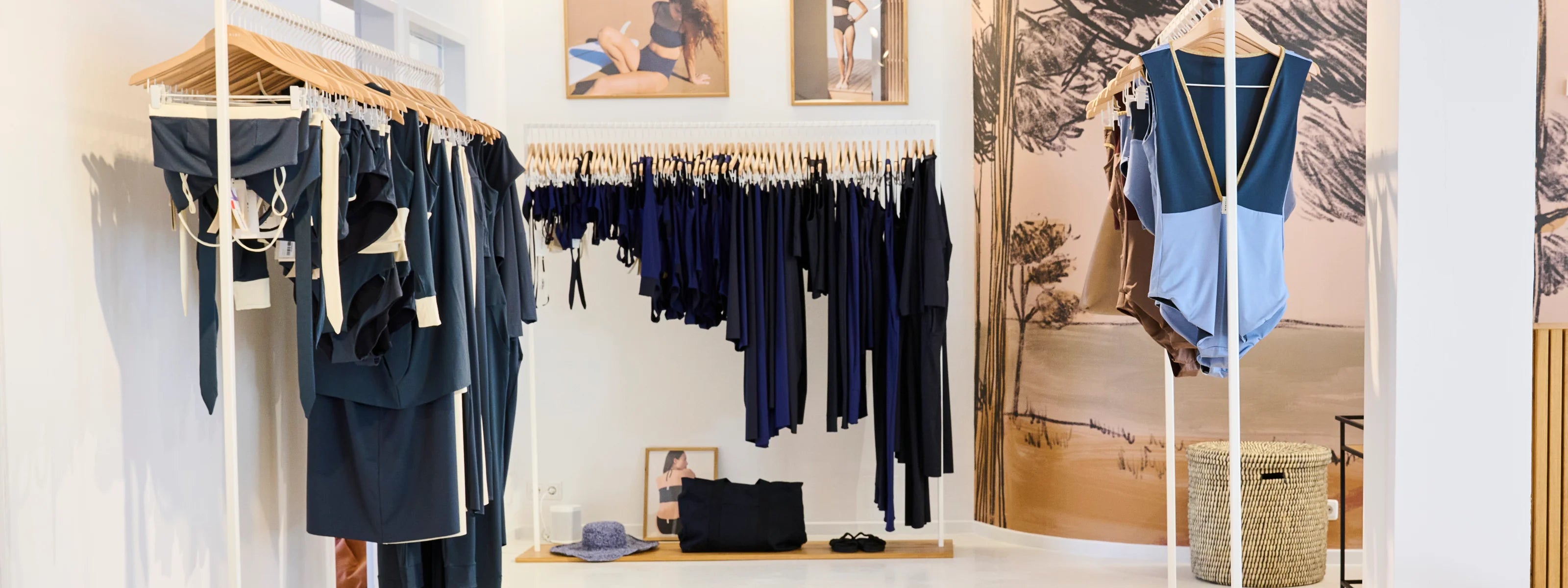MYMARINI-Shop mit Badeanzügen und Bikinis in Blau- und Schwarztönen, darunter ein One-Piece mit hohem Beinausschnitt.