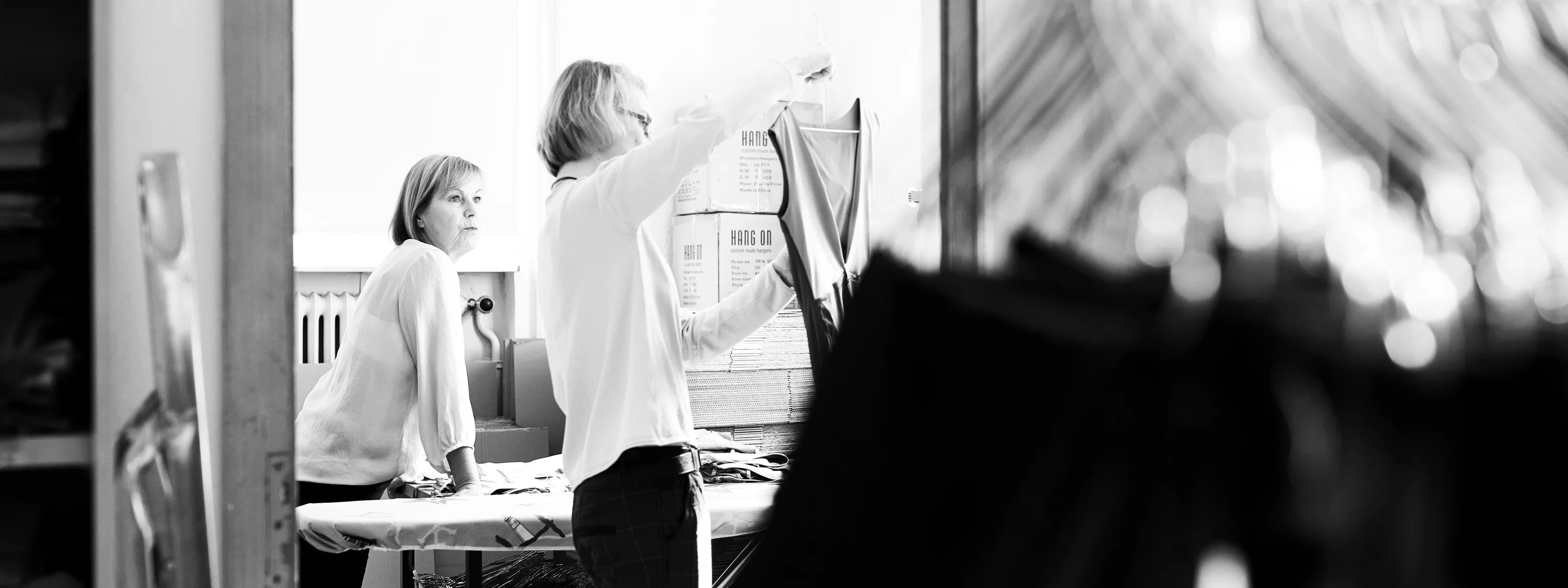 Zwei Personen arbeiten in einem Atelier an MYMARINI-Bademode. Eine Person hält ein Kleidungsstück hoch.