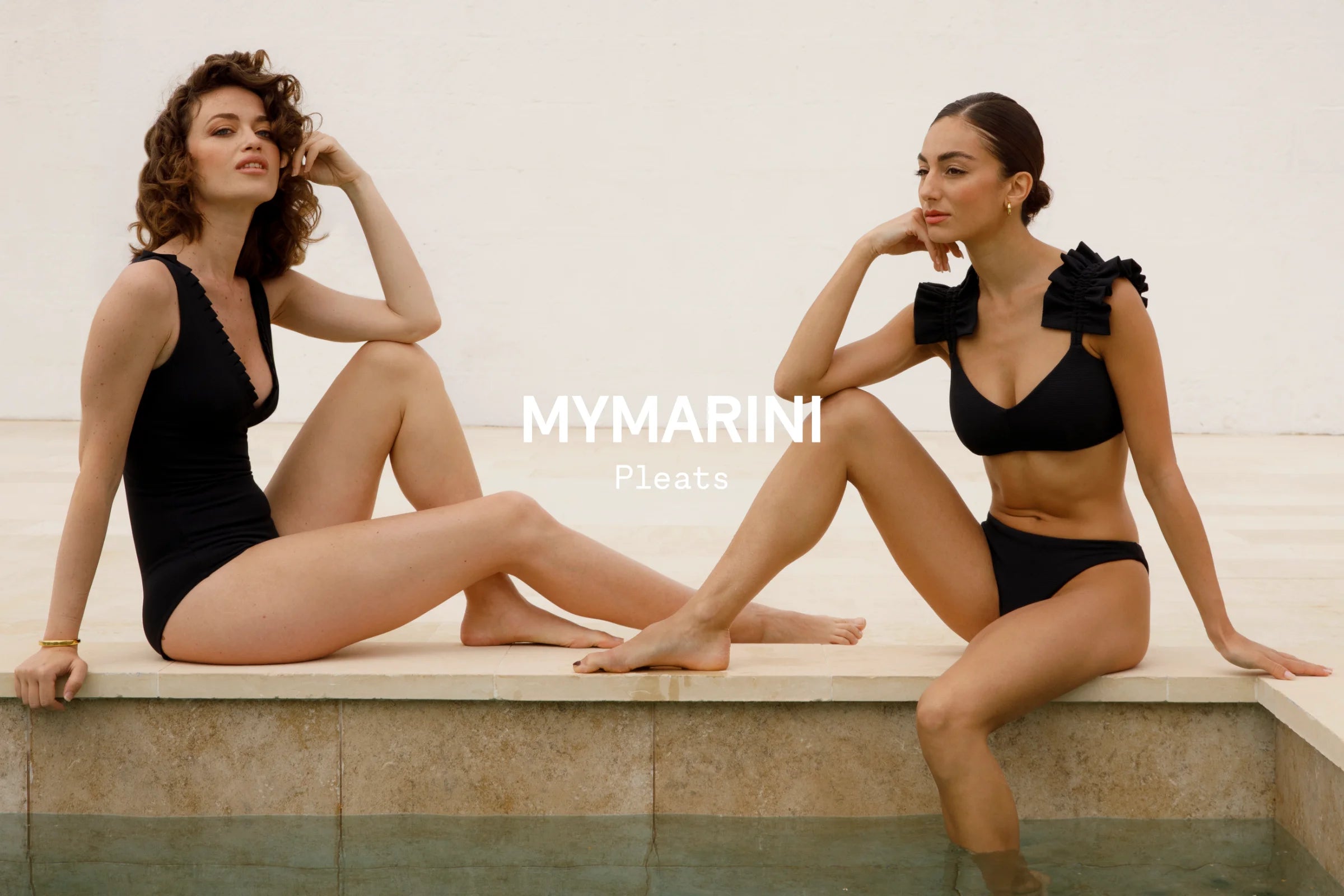 Zwei Frauen tragen MYMARINI-Bikinis mit V-Ausschnitt und breiten Trägern, sitzen am Poolrand.