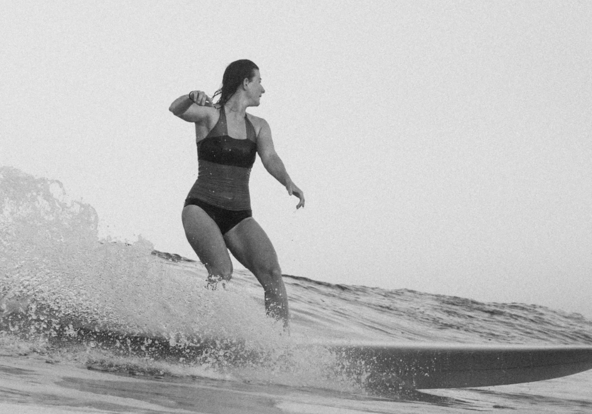Person surft auf einer Welle im MYMARINI Bikini mit Bandeau-Top und Mid rise Hose.