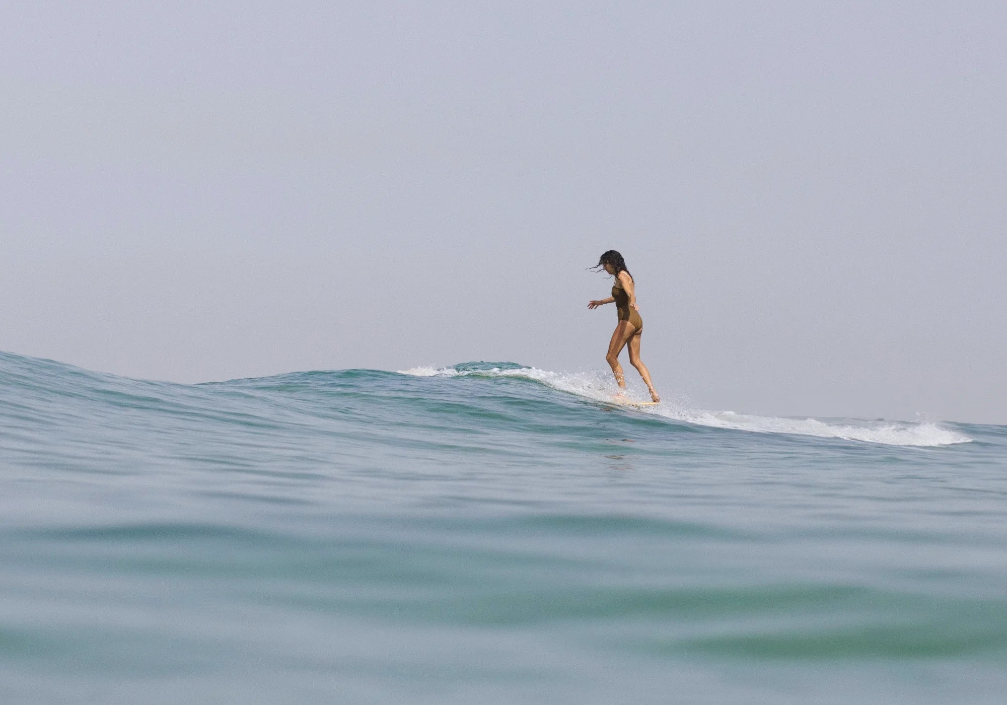Personen paddeln auf Surfbrettern im klaren Wasser, umgeben von Felsen.