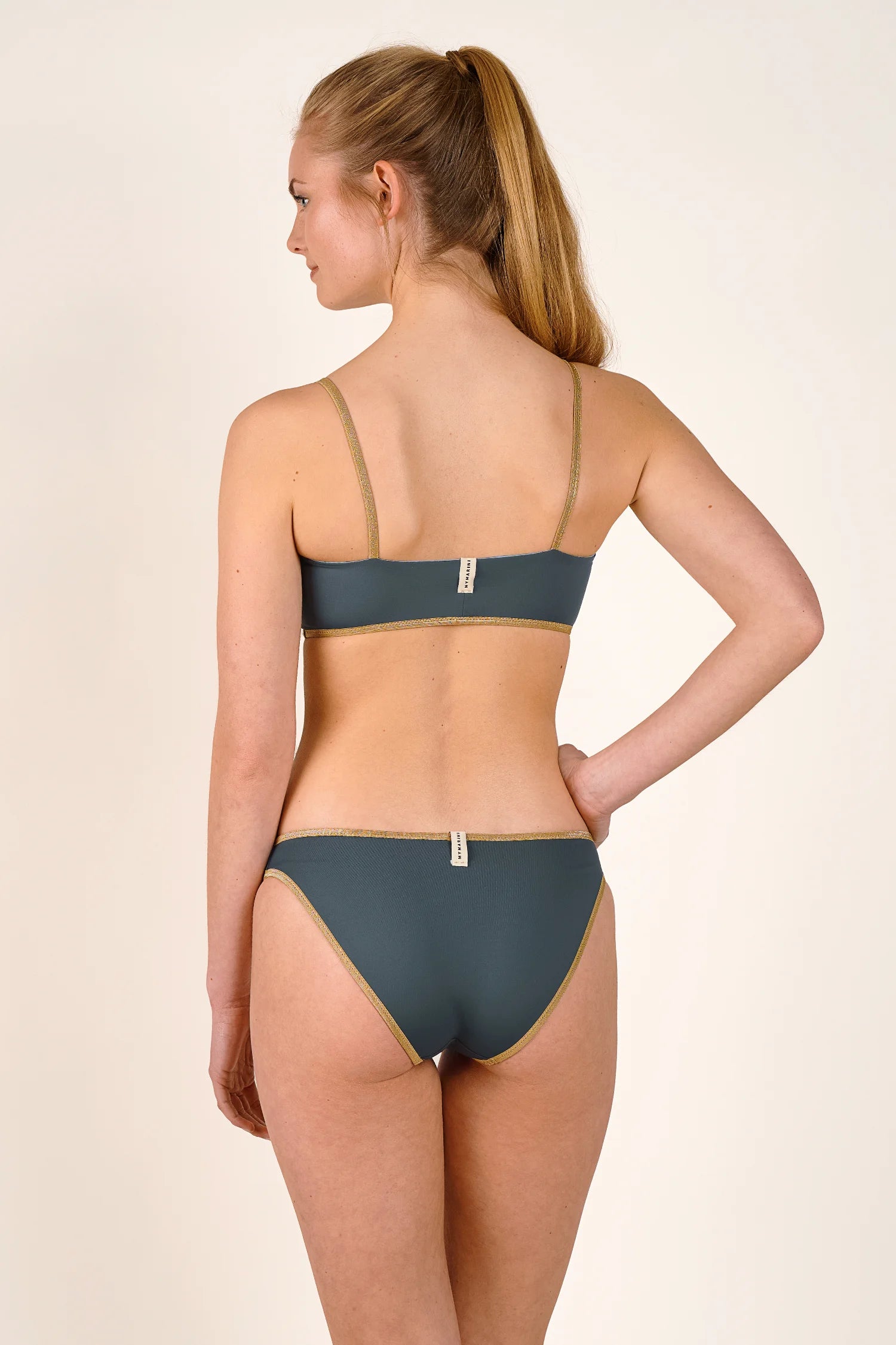 Bikinihose von MYMARINI in Dunkelgrün mit goldenen Akzenten, hoch geschnitten, von hinten sichtbar.#color_crystal-grey