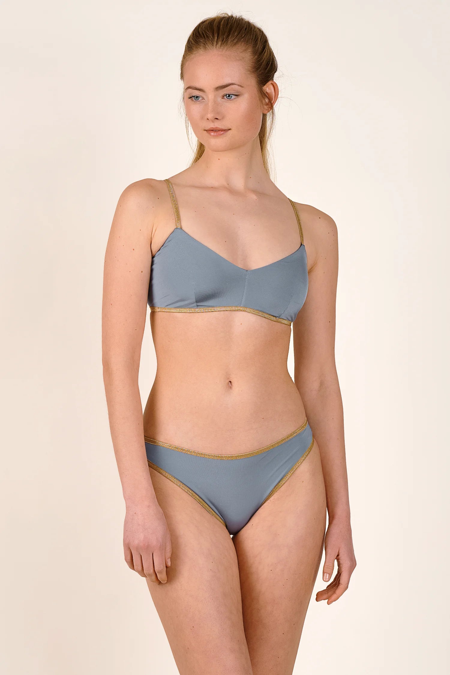 Bikinioberteil und -hose von MYMARINI in Grau mit goldenen Akzenten, V-Ausschnitt und breiten Trägern.#color_crystal-grey