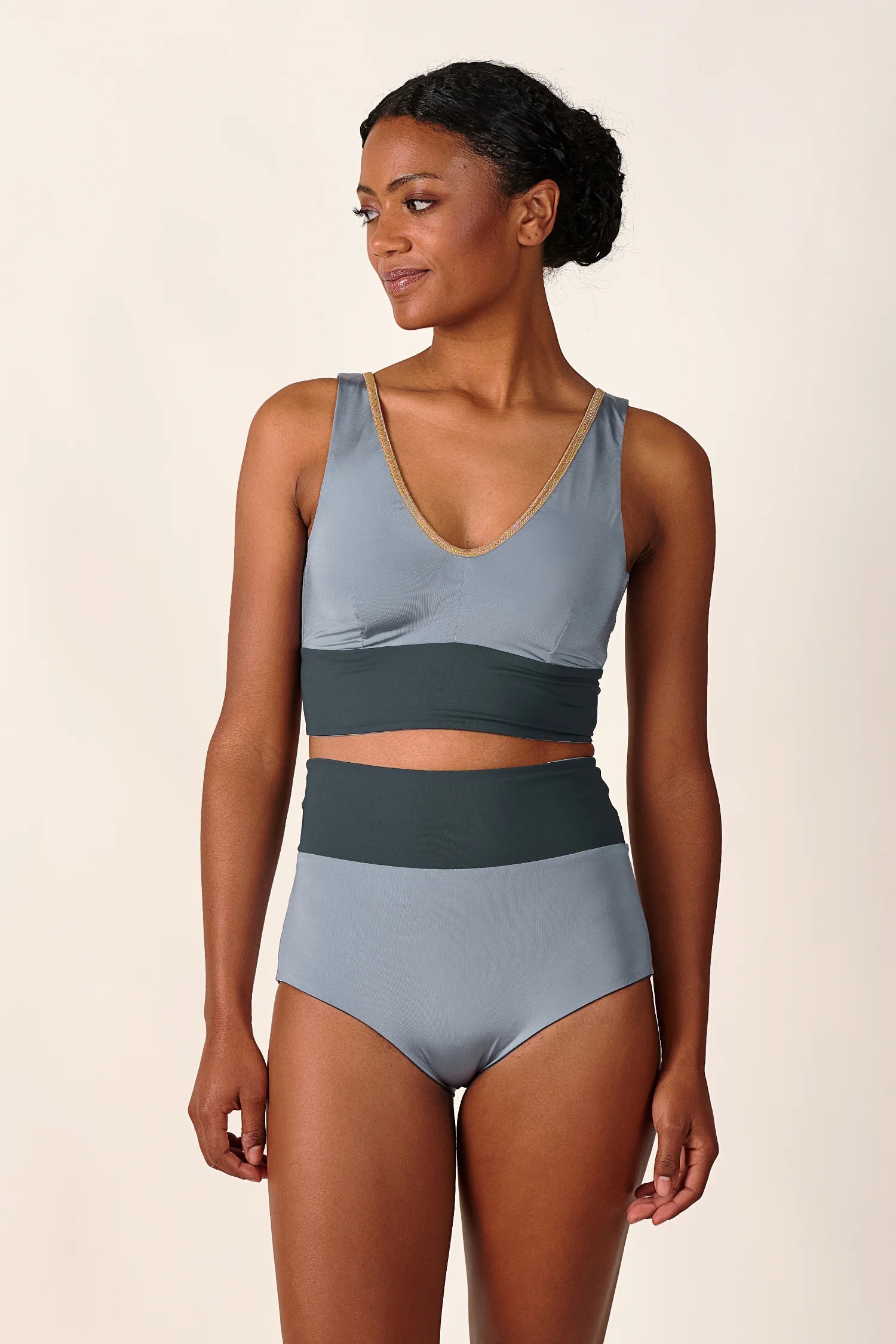 Frau trägt MYMARINI Bikinitop mit V-Ausschnitt und Bikinihose mit hohem Bund in Grau.#color_crystal-grey