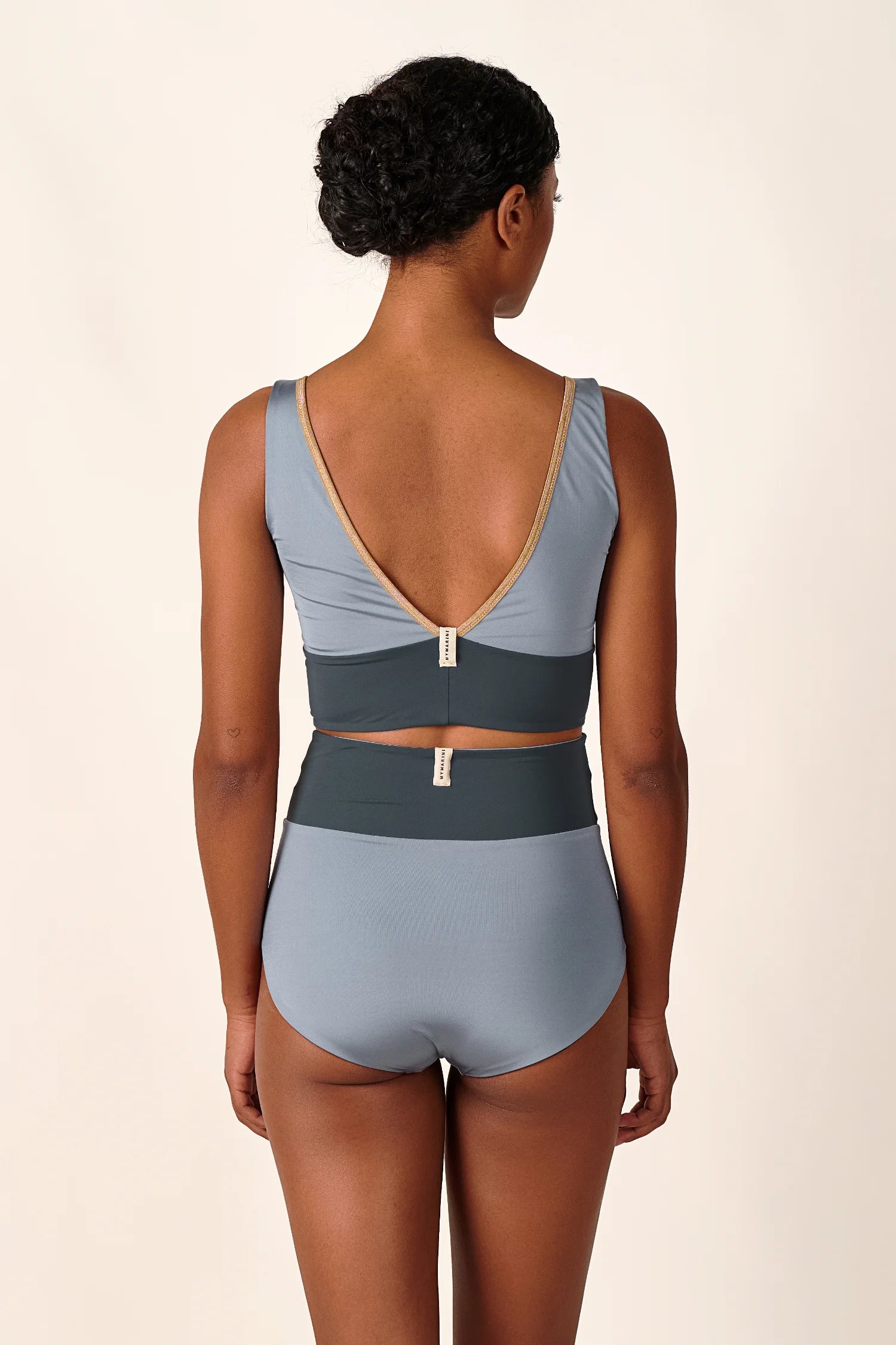 Bikinitop und Bikinihose von MYMARINI in Blau mit tiefem Rückenausschnitt und hohem Beinausschnitt, von hinten fotografiert.#color_crystal-grey