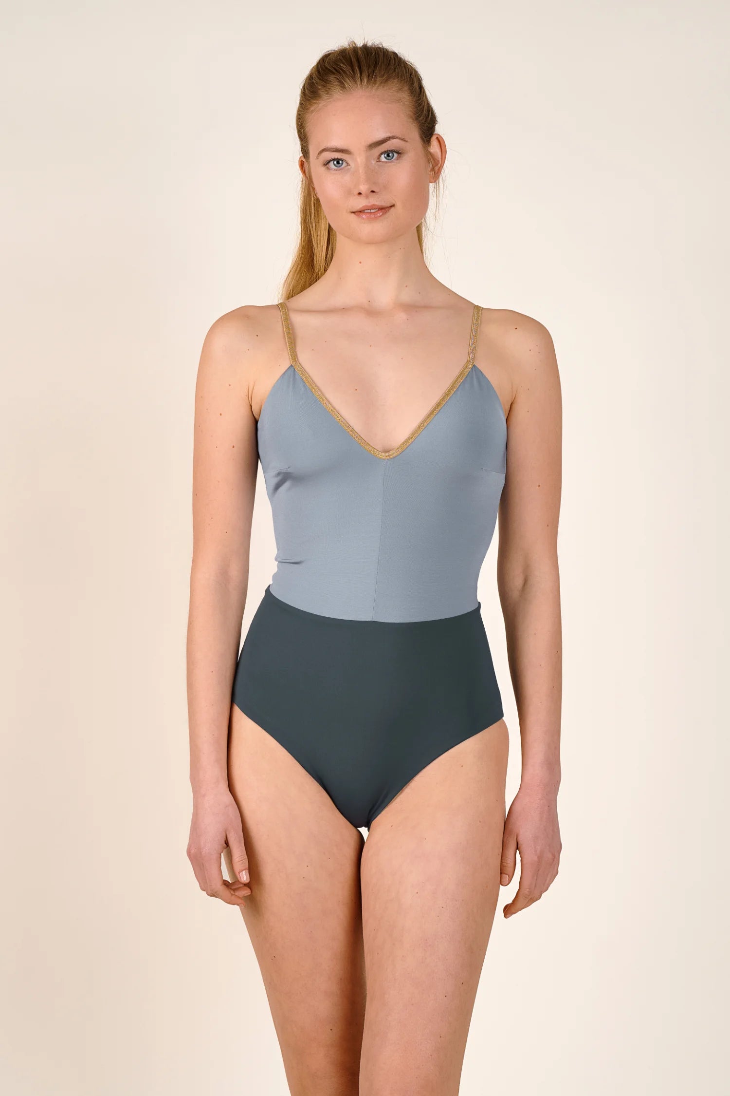 Frau trägt MYMARINI Badeanzug mit V-Ausschnitt und hohem Beinausschnitt in Grau und Blau.#color_crystal-grey