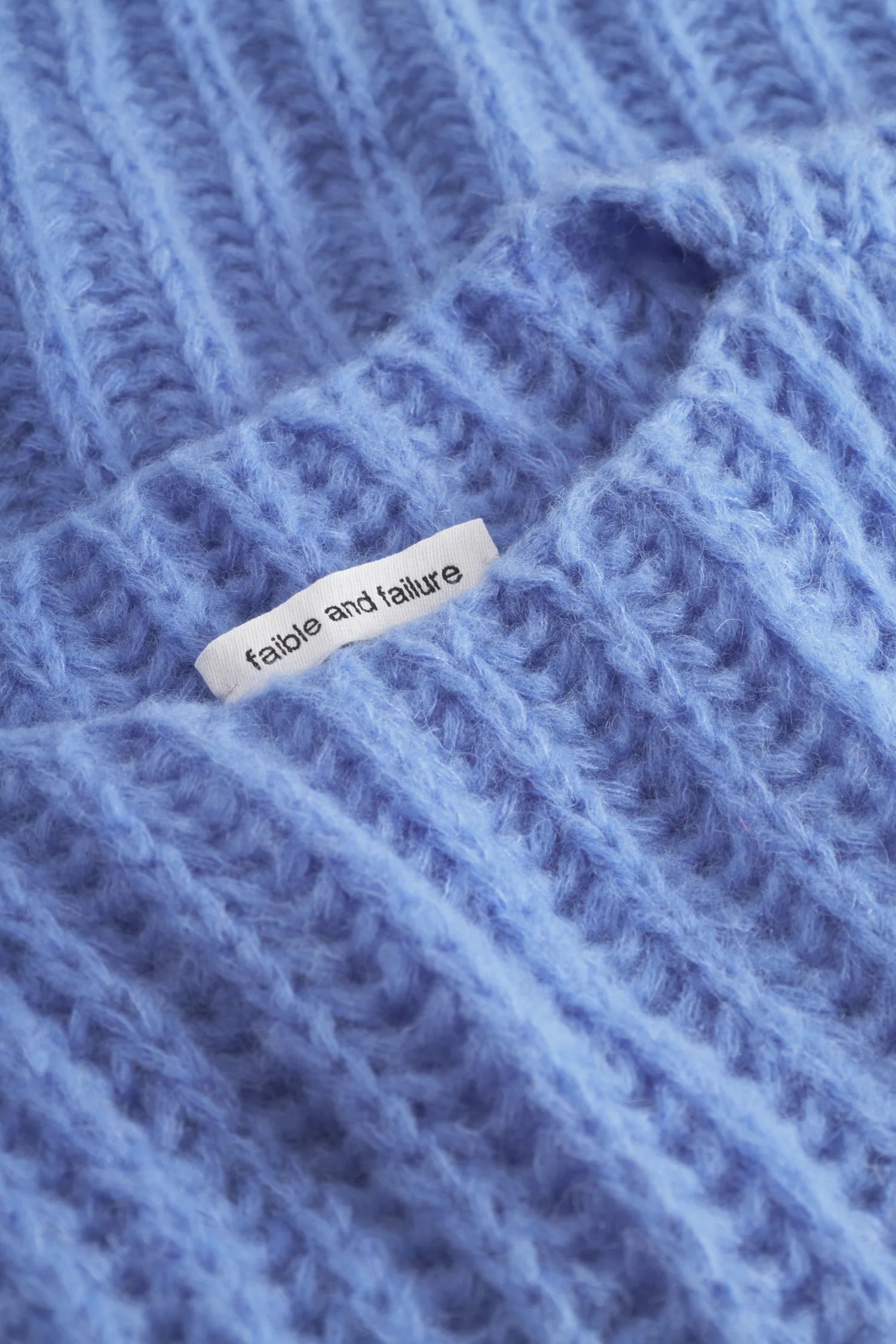 Strickpullover in Blau mit sichtbarem Etikett von "faible and failure".#color_capri