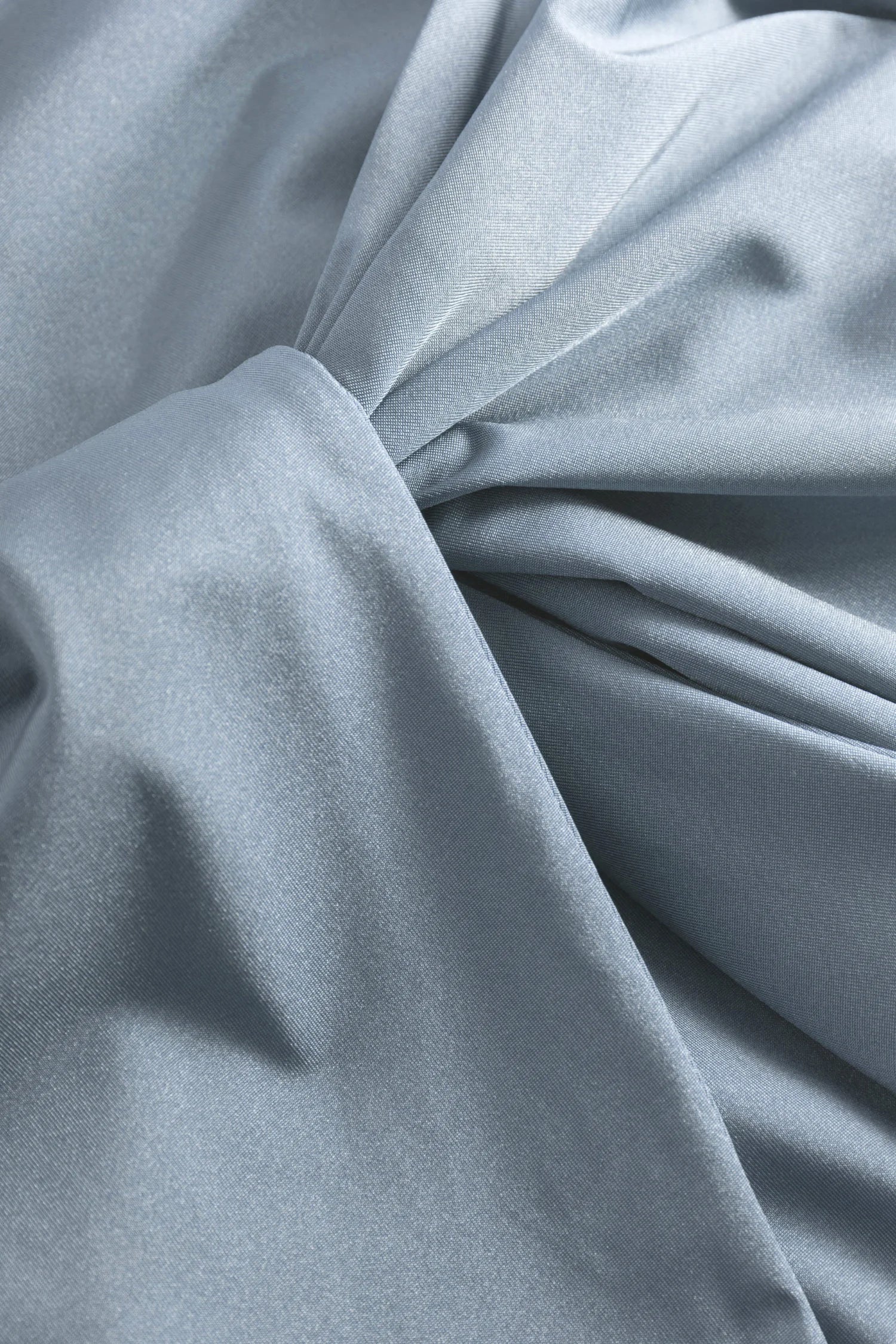 Nahaufnahme eines hellblau schimmernden Stoffes mit sanften Falten; sichtbare Textur, neutraler Hintergrund für Produkte.#color_crystal