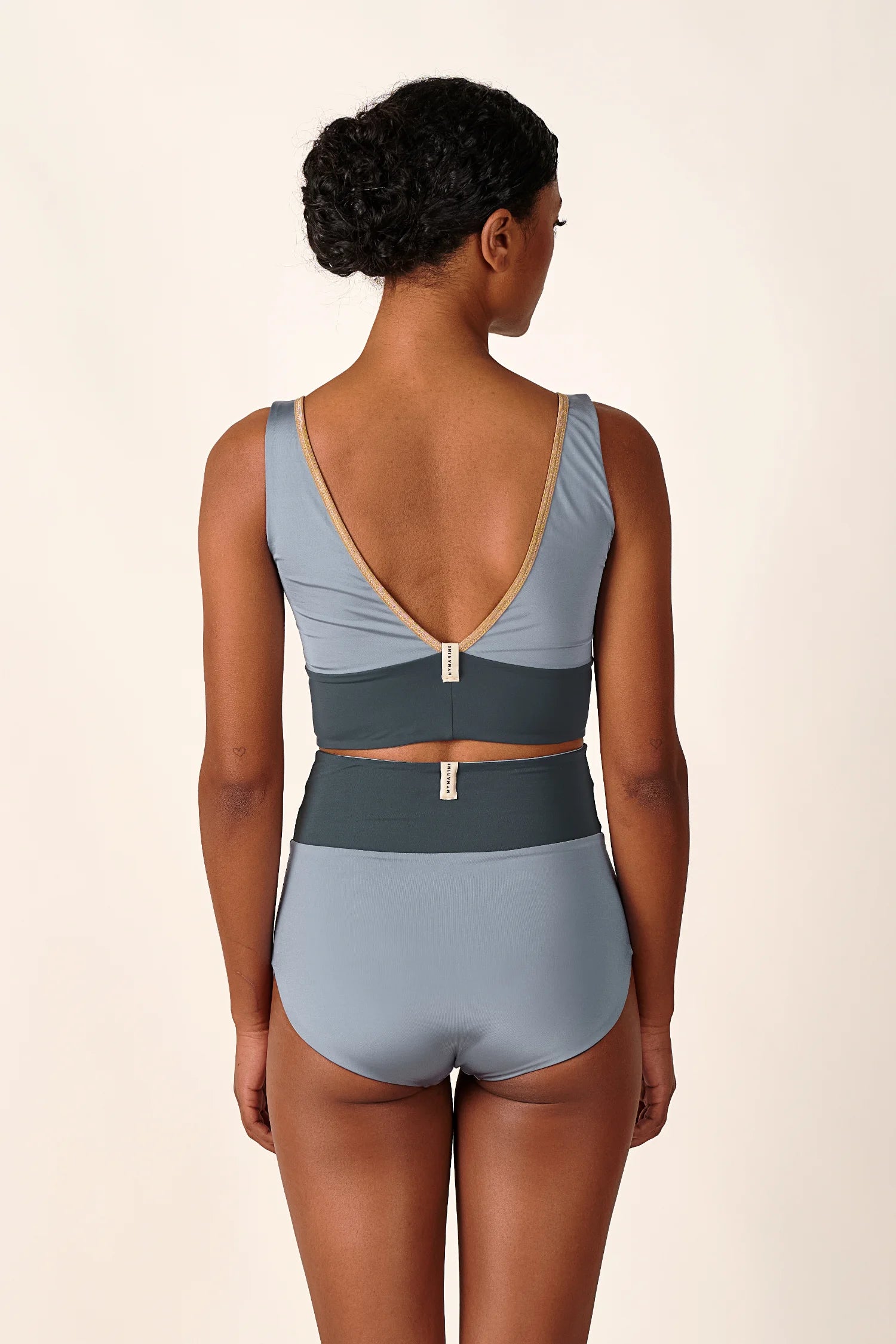 Frau in MYMARINI Bikini mit V-Ausschnitt und High Waist Schnitt, Rückansicht.#color_crystal-grey