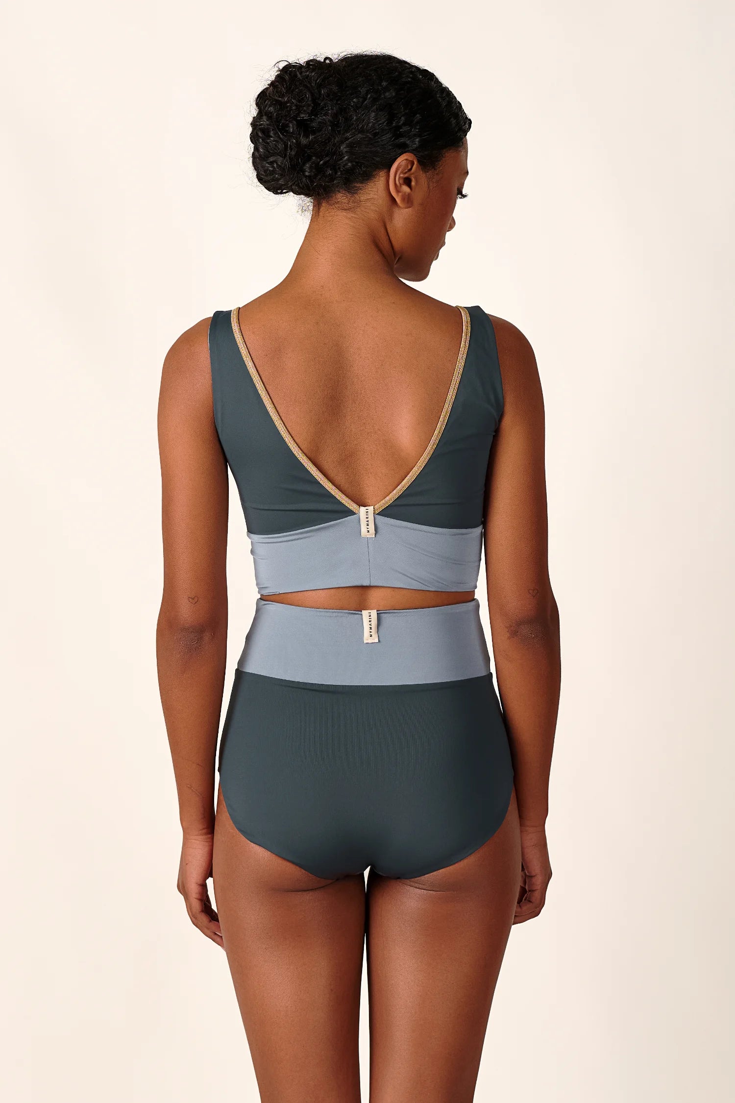 Person von hinten in MYMARINI Bikini mit V-Ausschnitt und High Waist Schnitt in Blau- und Beigetönen.#color_crystal-grey