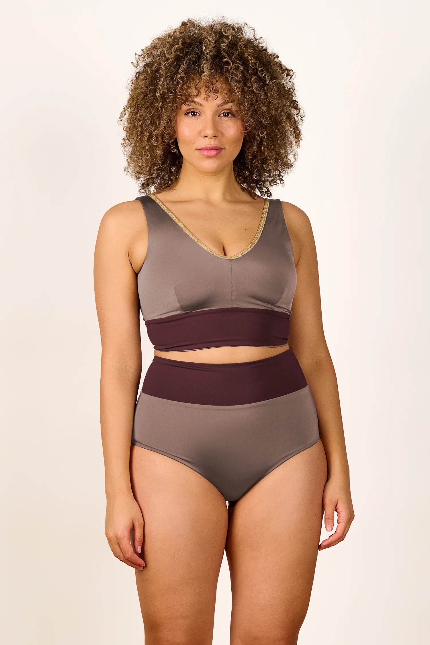 Frau trägt MYMARINI Bikini mit V-Ausschnitt und High Waist Schnitt in Braun- und Beigetönen.#color_shimmer-brown