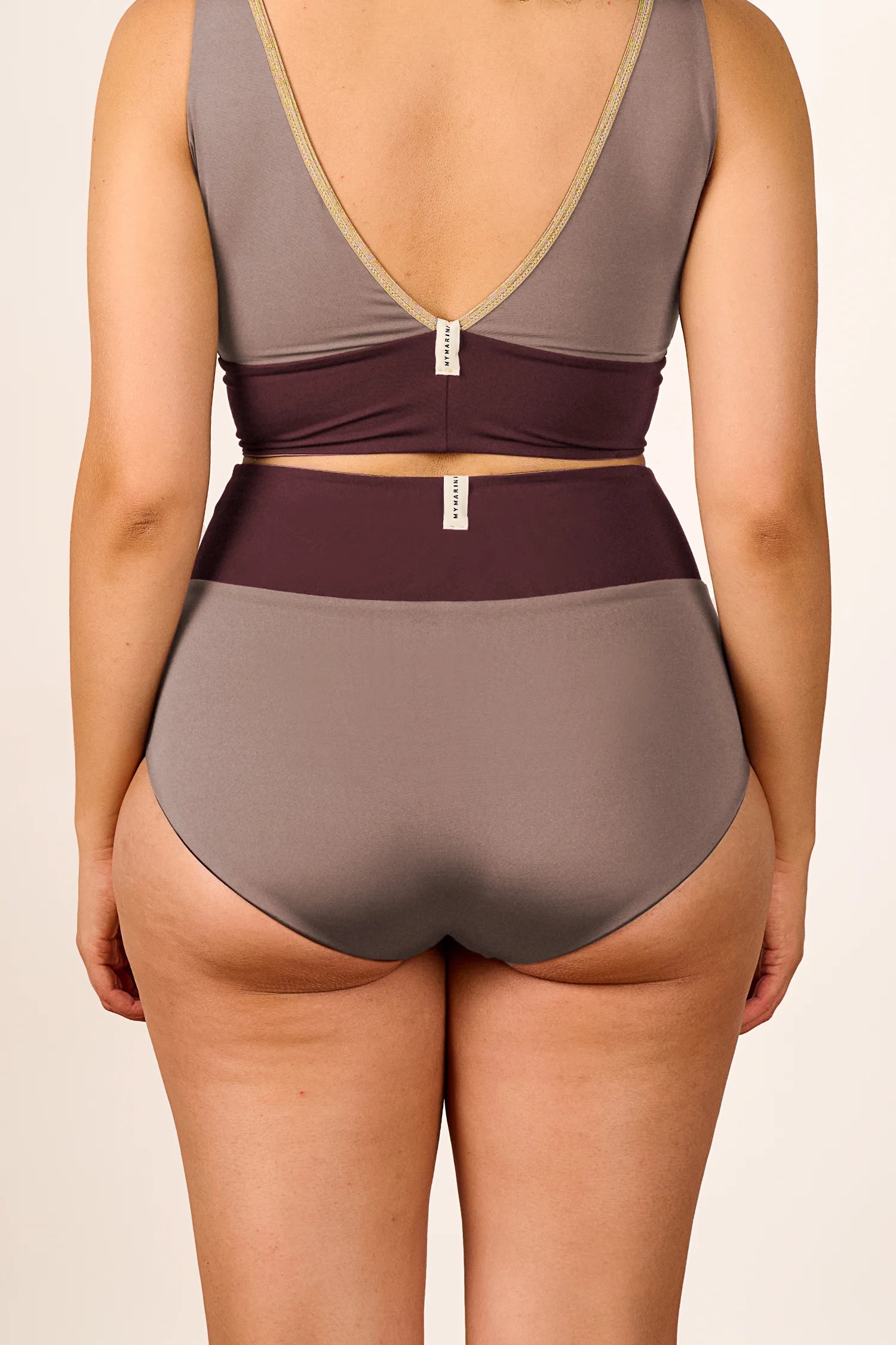 Rückansicht einer Person in einem MYMARINI Bikini mit V-Ausschnitt und High Waist Schnitt in Braun- und Beigetönen.#color_shimmer-brown
