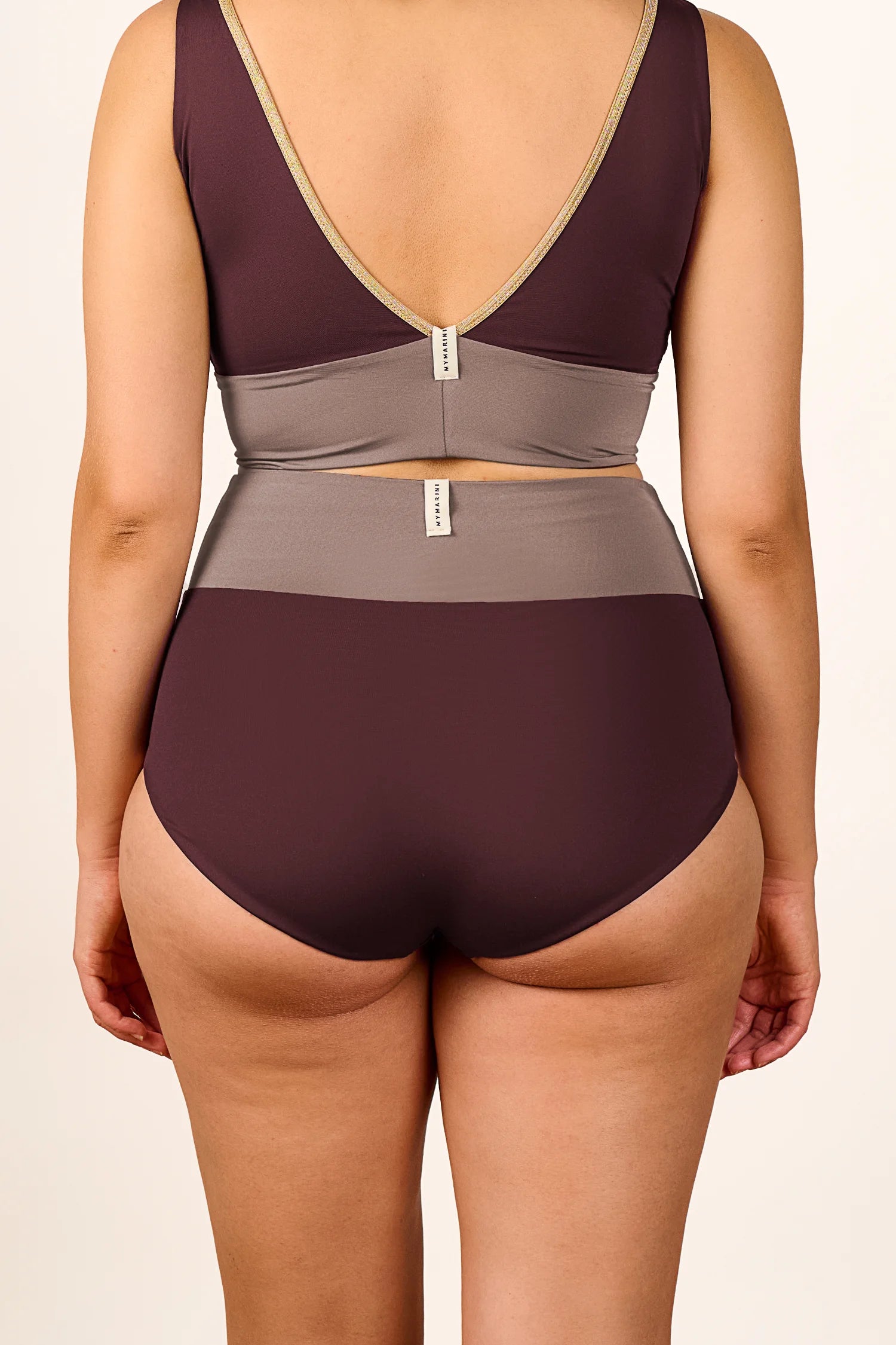 Rückansicht einer Frau in einem MYMARINI Bikini mit V-Ausschnitt und hohem Beinausschnitt in Braun- und Grautönen.#color_shimmer-brown