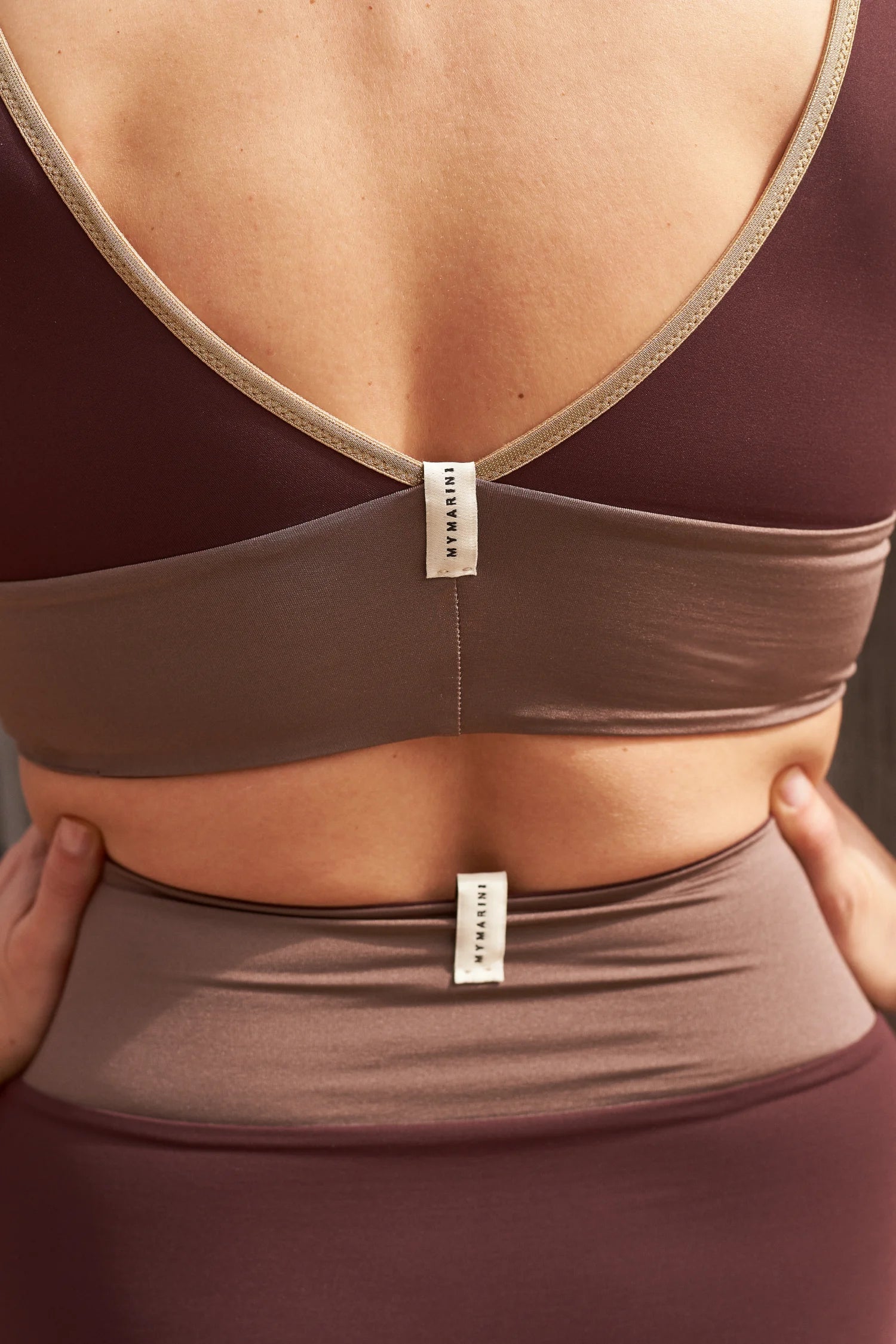 Rückenansicht eines MYMARINI-Bikinitops mit V-Ausschnitt und einer Bikinihose mit hohem Bund in Braun- und Beigetönen.#color_shimmer-brown