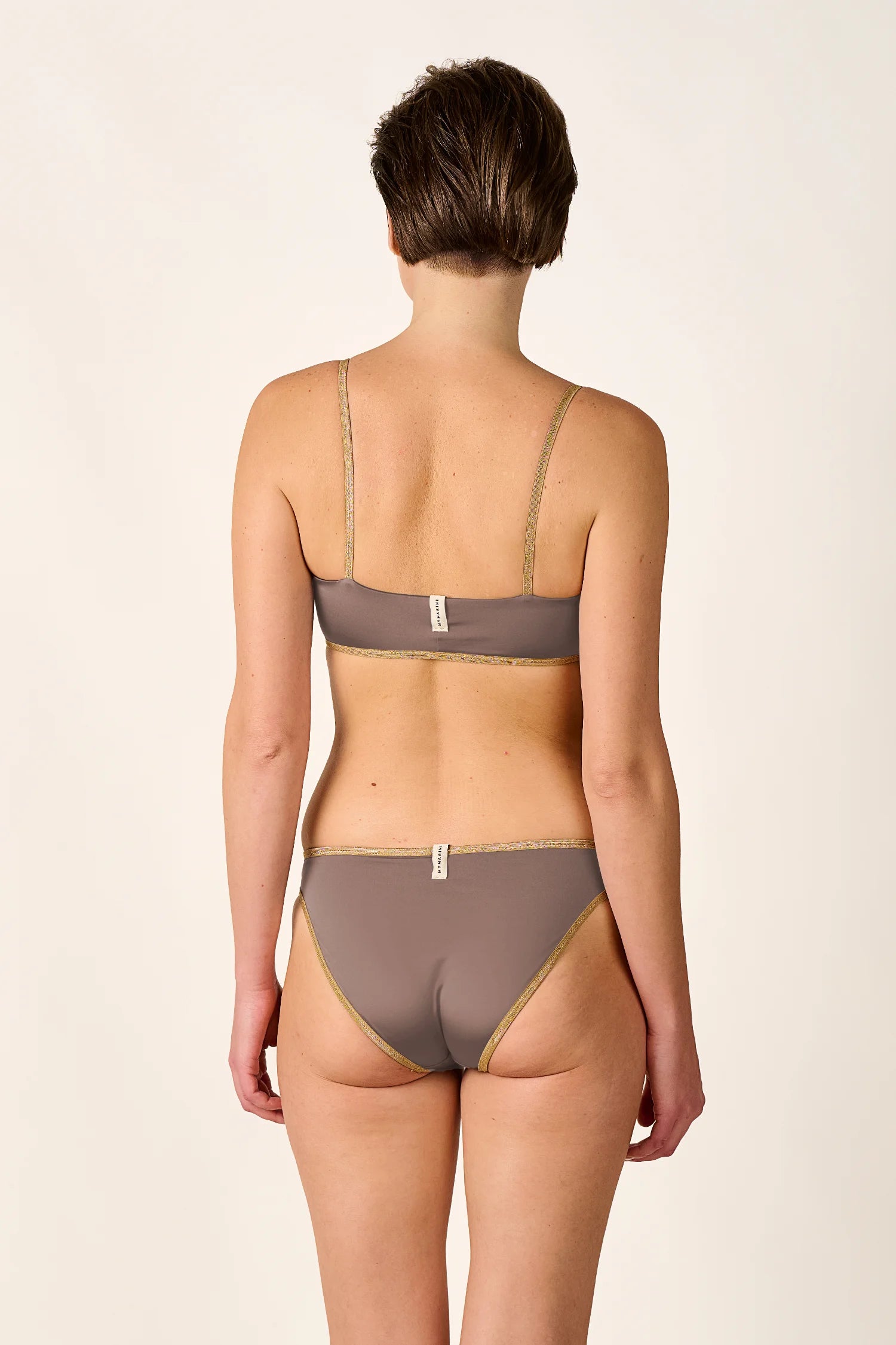 Rückansicht einer Frau in einem MYMARINI Bikini mit Spaghettiträgern und hohem Beinausschnitt in Braun.#color_shimmer-brown