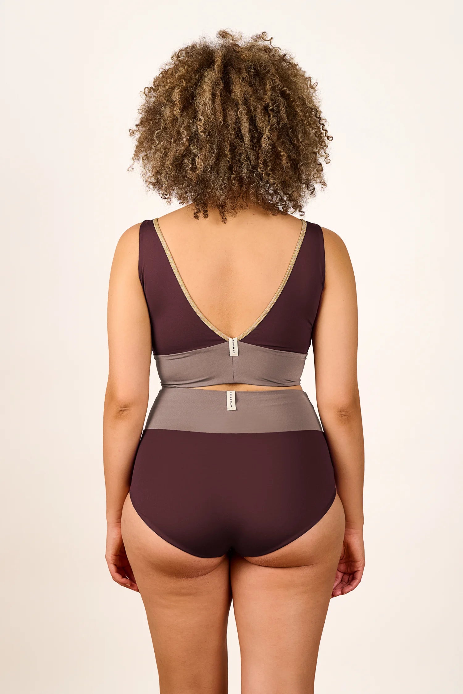 Person trägt einen MYMARINI Badeanzug mit V-Ausschnitt und breiten Trägern in Braun und Beige. Rückansicht.#color_shimmer-brown