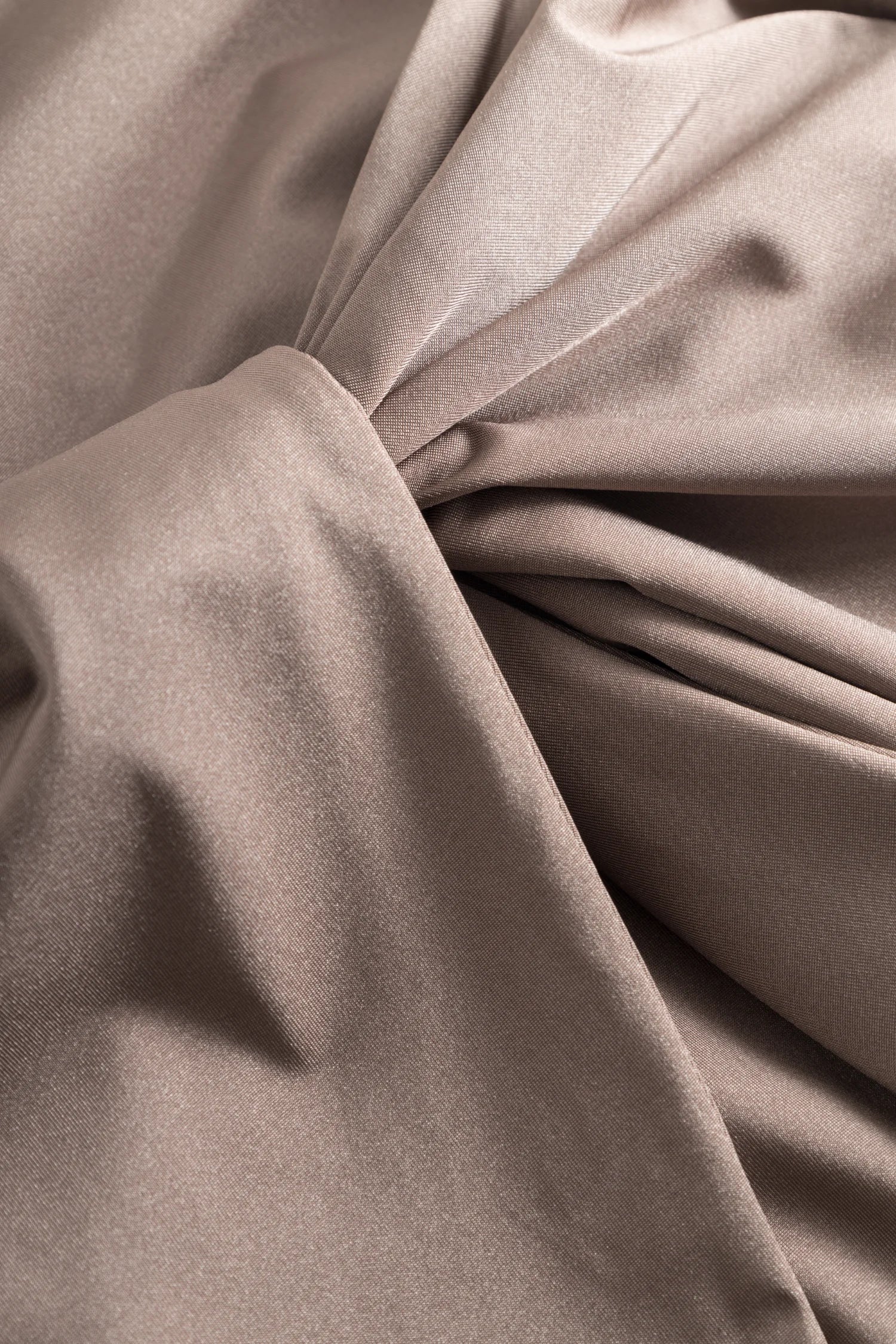 Nahaufnahme taupefarbener Satin-Stoff mit glatter Oberfläche und Faltlinien; Textur deutlich sichtbar.#color_grey