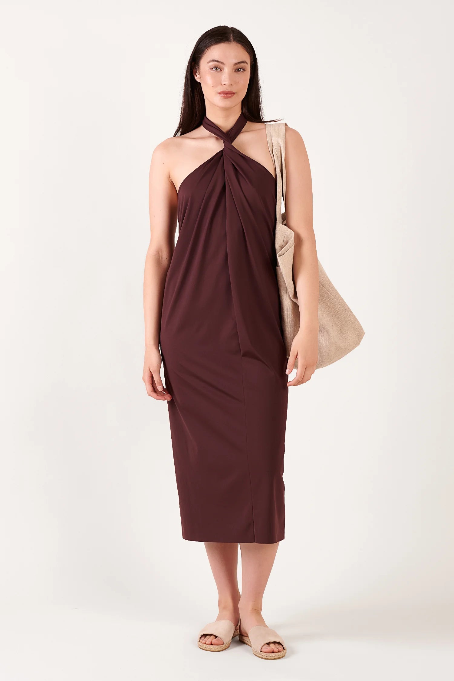 MYMARINI Kleid in Burgunderrot, Neckholder mit verdrehtem Frontdetail; beige Tote-Tasche und Sandaletten sichtbar.#color_chocolate