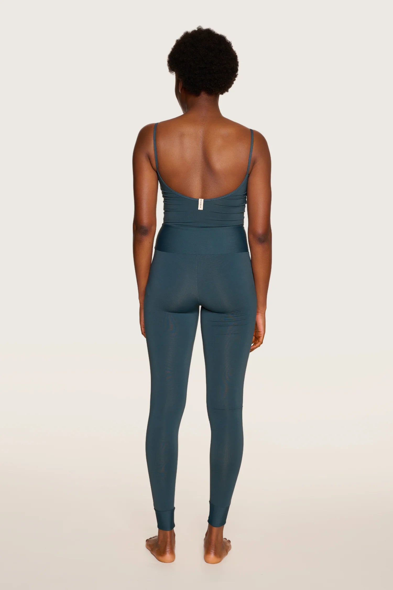 Person von hinten in MYMARINI One-Piece mit tiefem Rückenausschnitt und Spaghettiträgern in Dunkelblau.#color_grey