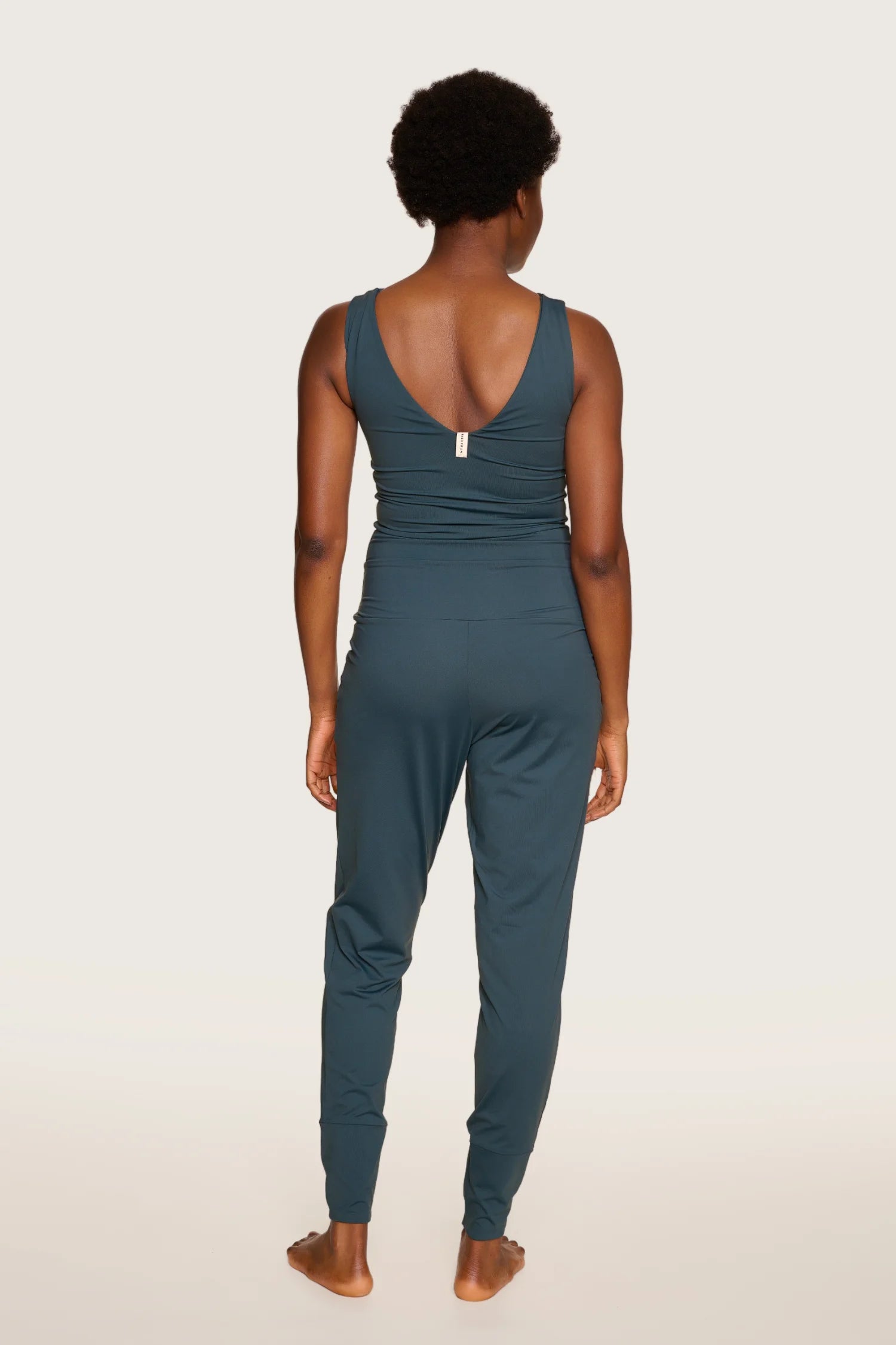 Person von hinten in einem MYMARINI Jumpsuit mit V-Ausschnitt und breiten Trägern, in dunklem Blau.#color_grey