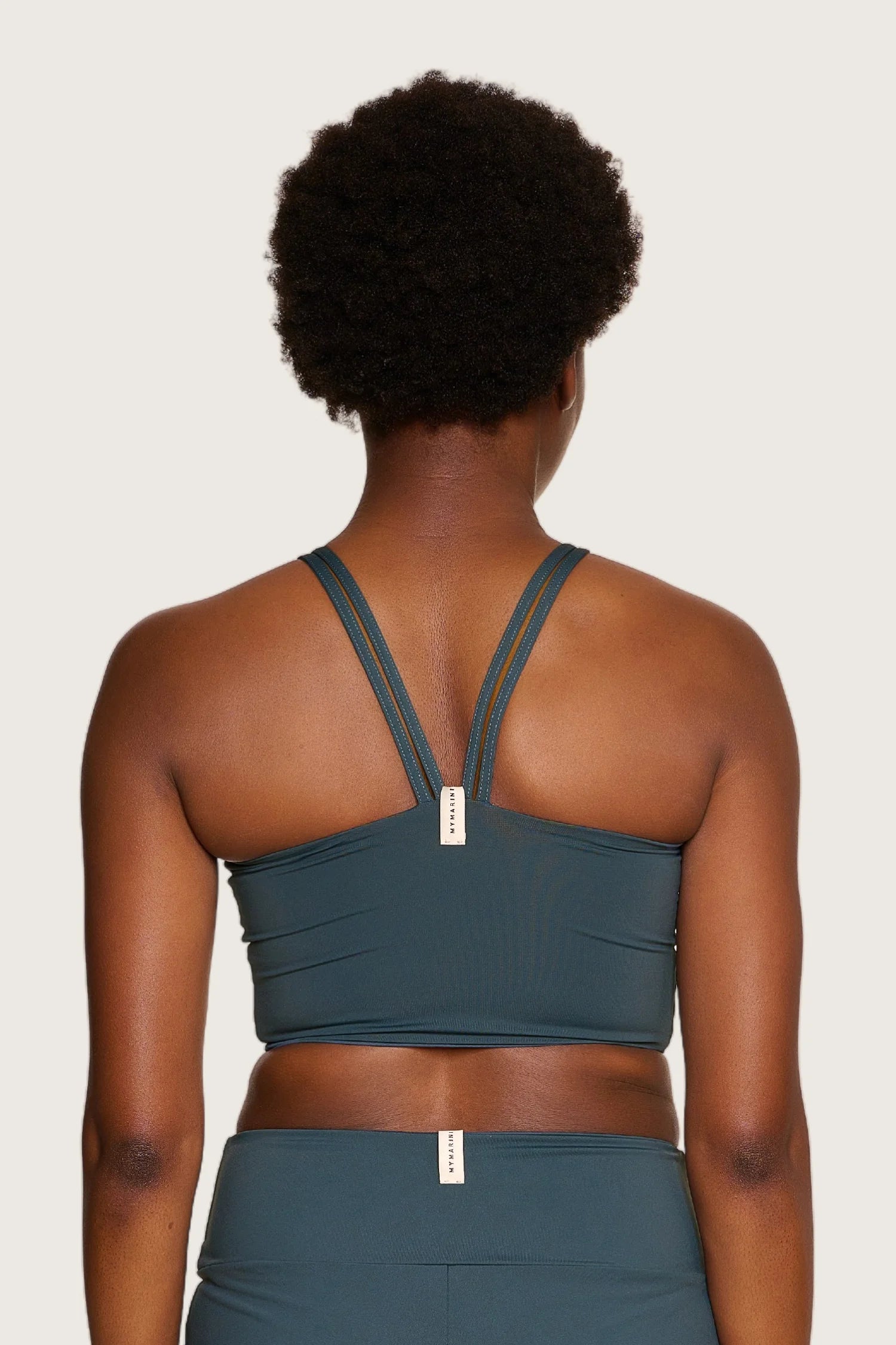 Rückansicht einer Person in einem MYMARINI Bikinitop mit breiten Trägern und einer Bikinihose, beide in dunklem Grün.#color_grey