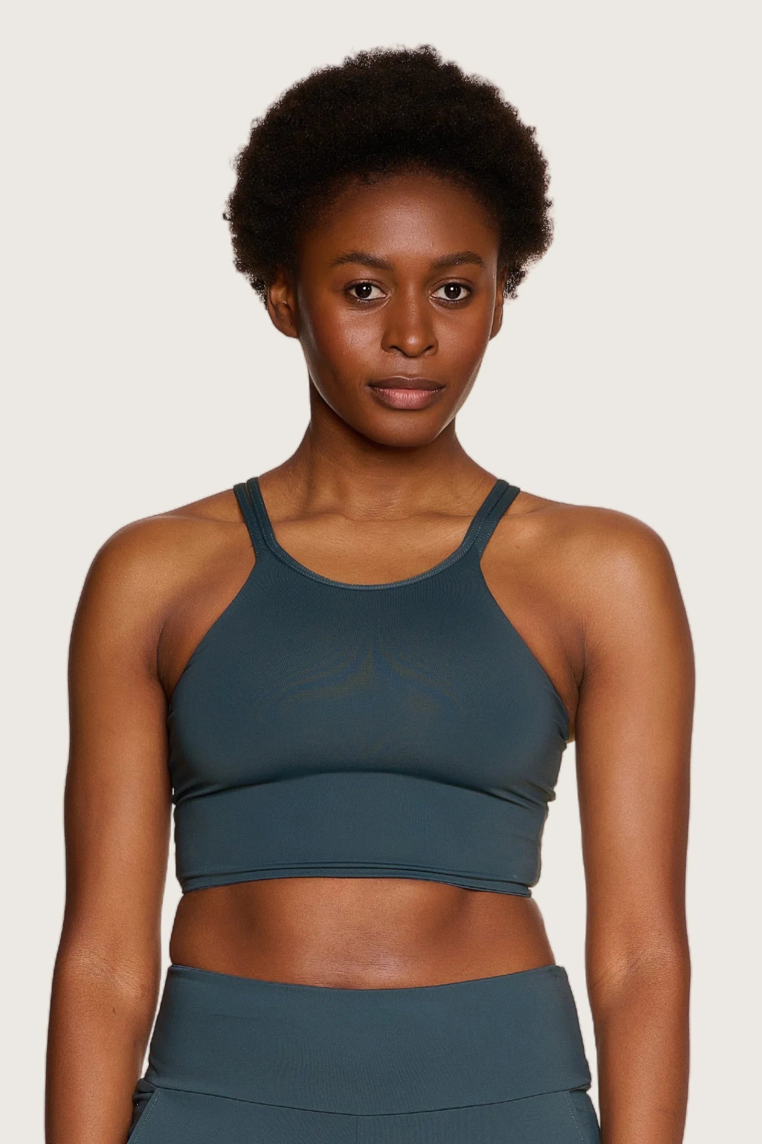 Person trägt ein MYMARINI Bikinitop mit hohem Ausschnitt und breiten Trägern in Dunkelgrün.#color_grey