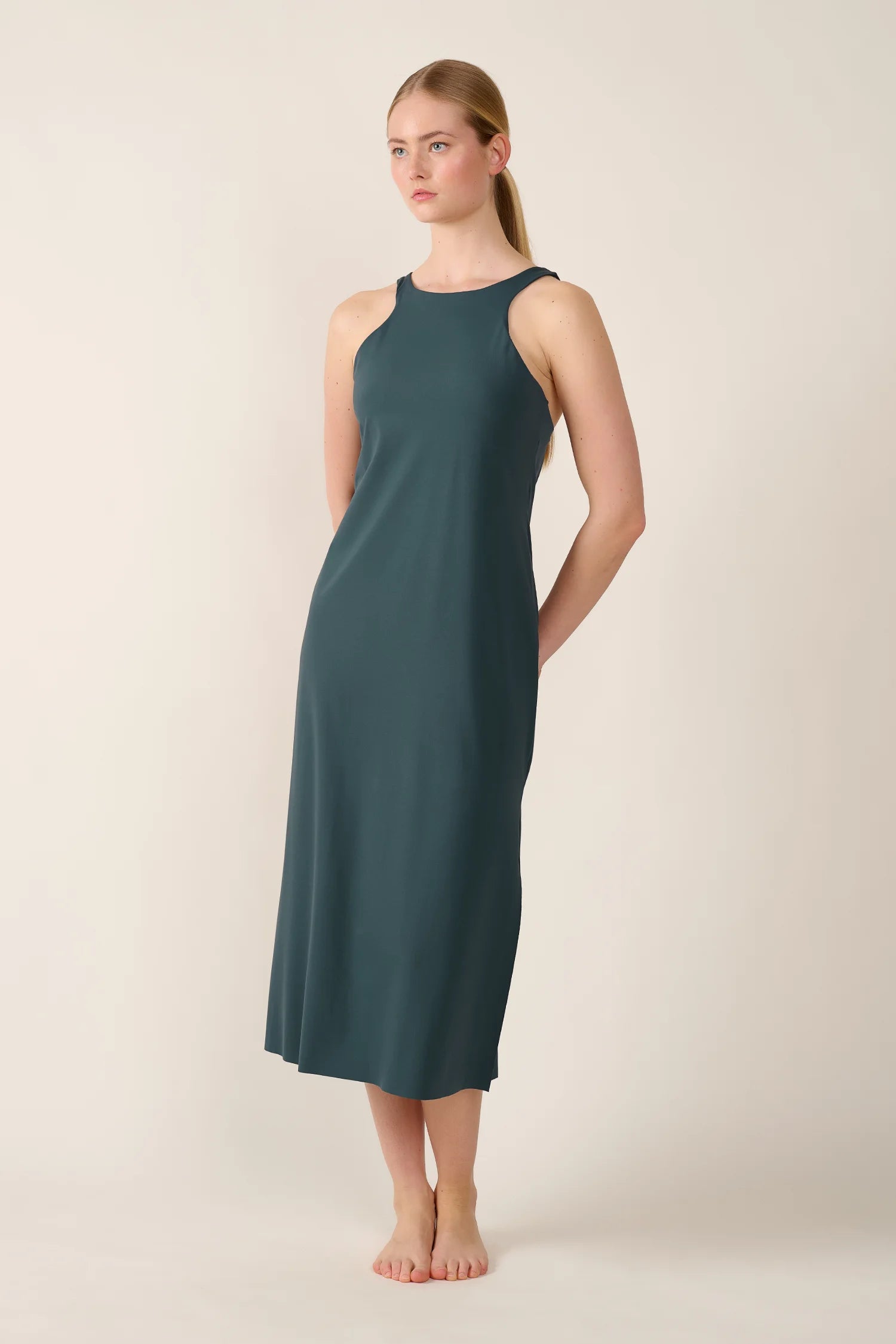 Frau trägt ärmelloses, hochgeschlossenes MYMARINI-Kleid in Dunkelgrün.#color_grey