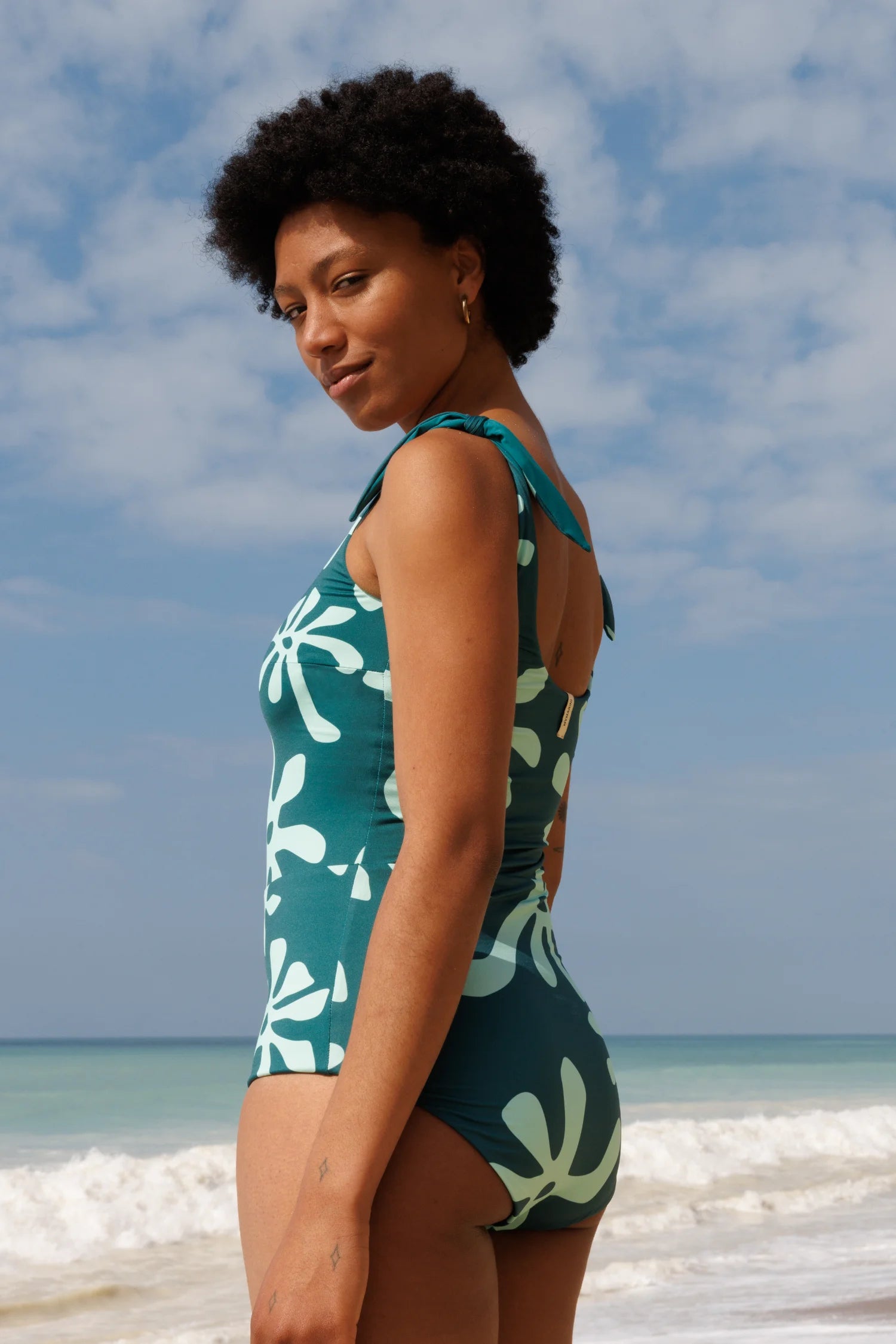 Badeanzug von MYMARINI mit hoch geschlossenem Schnitt und floralem Muster, getragen von einer Person am Strand.#color_jungle-print