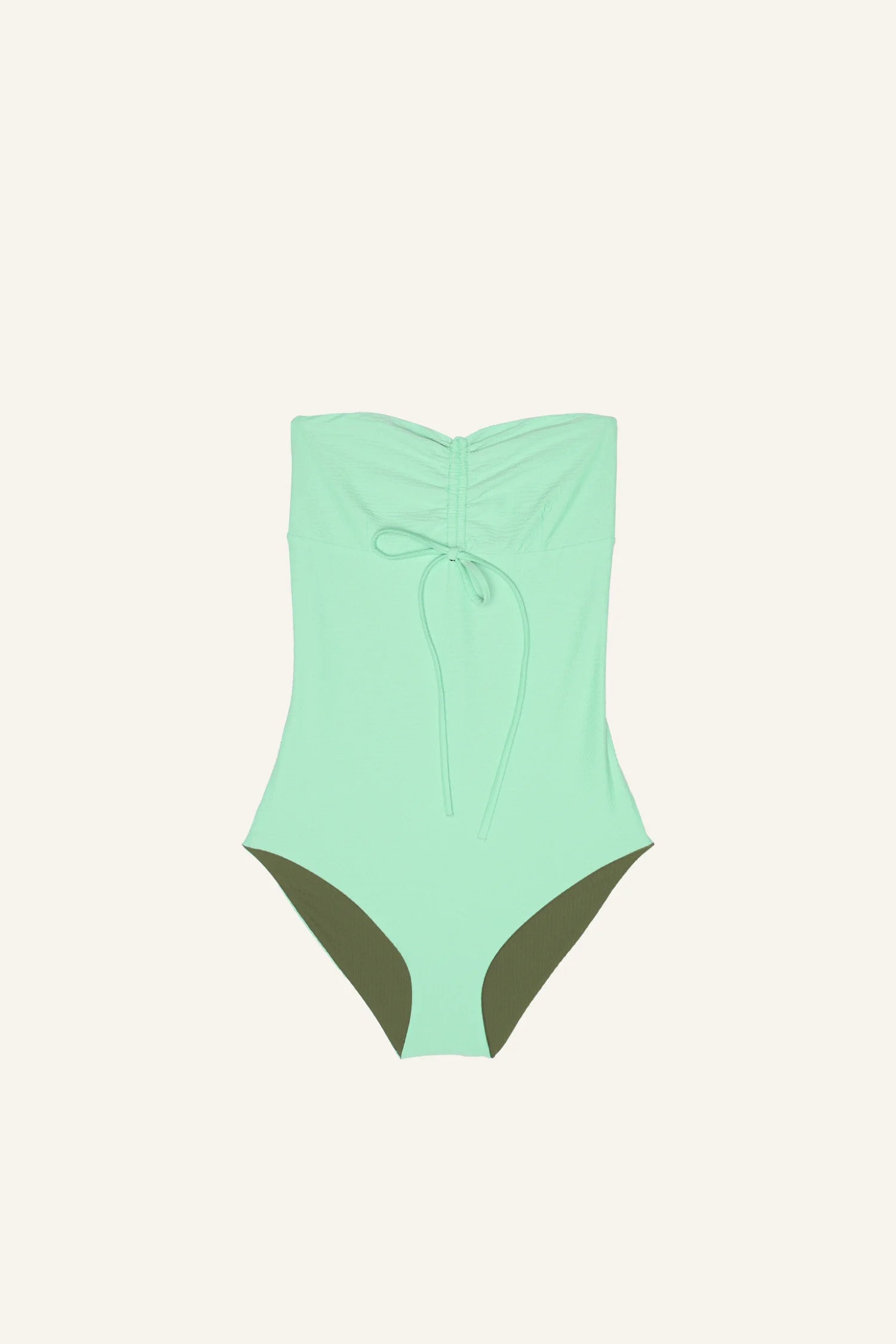 Mintgrüner MYMARINI One-Piece mit Bandeau-Schnitt und hohem Beinausschnitt auf cremefarbenem Hintergrund.#color_lagoon-seaweed