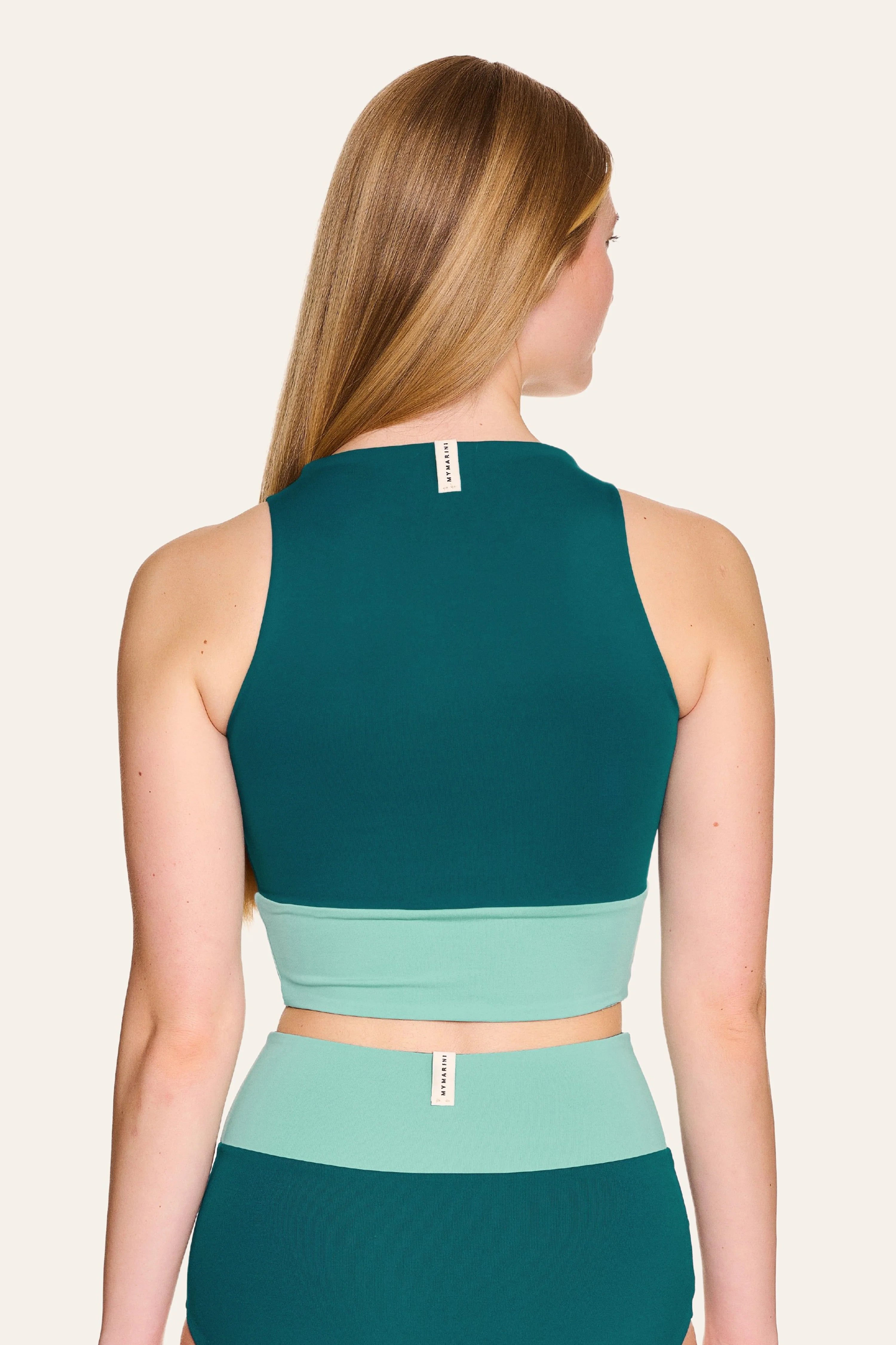 Frau in MYMARINI Bikinitop mit breiten Trägern und Bikinihose, beide in Grün- und Minttönen, von hinten gezeigt.#color_eucalyptus-petrol