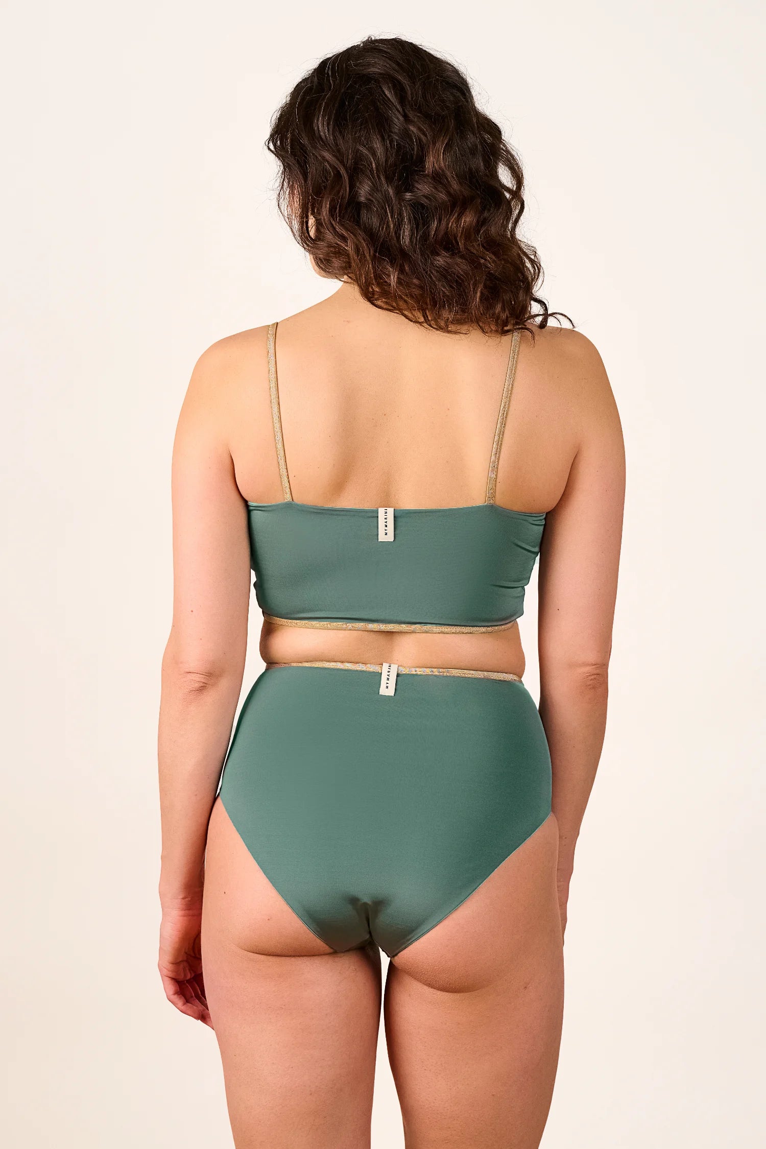 Rückansicht einer Frau in einem MYMARINI Bikini mit Bandeau-Top und High-Waist-Hose in Grün, schmale Träger.#color_lagoon-teal