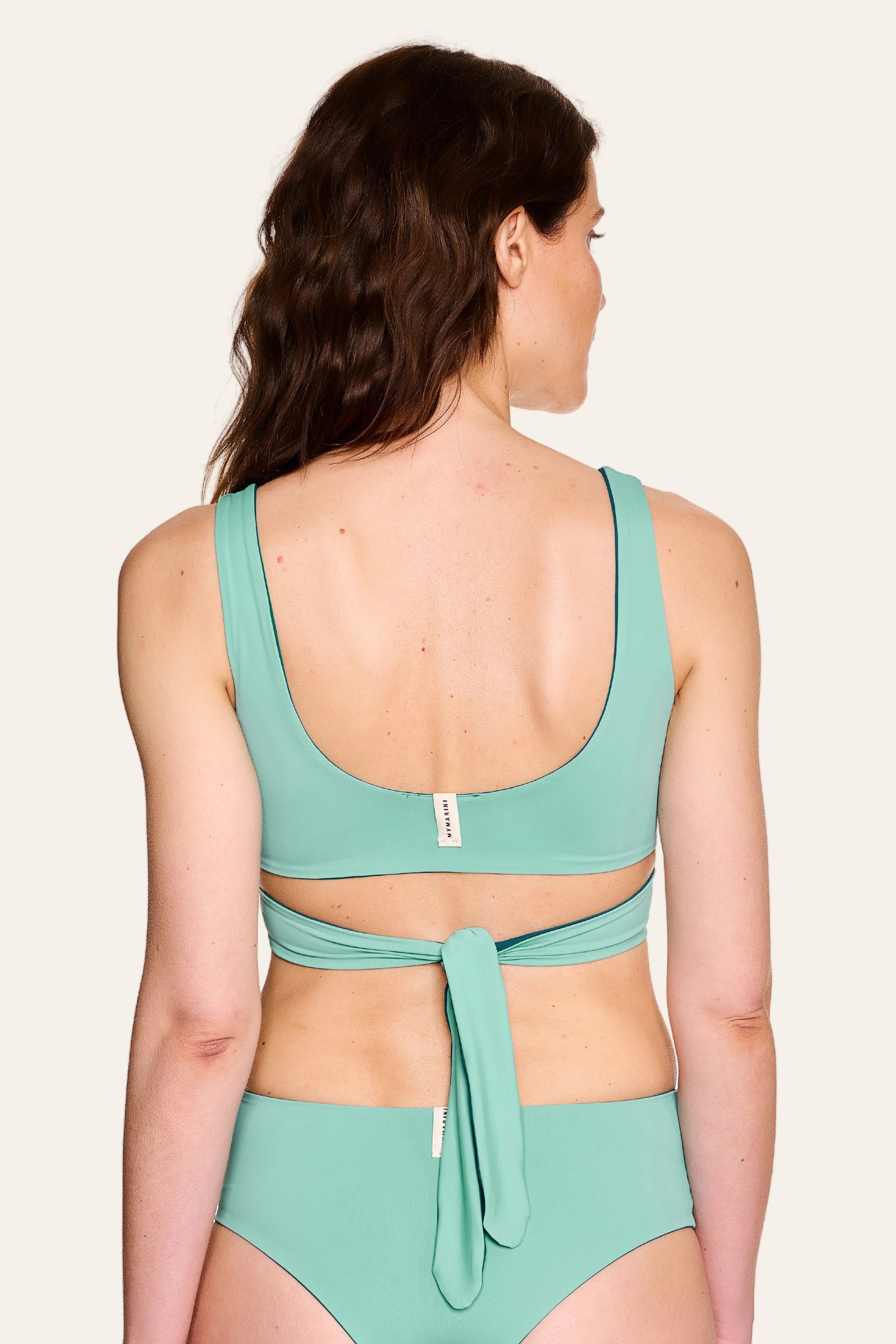 Frau trägt MYMARINI Bikini mit breiten Trägern und hohem Beinausschnitt in Mintgrün, Rückansicht.#color_eucalyptus-petrol