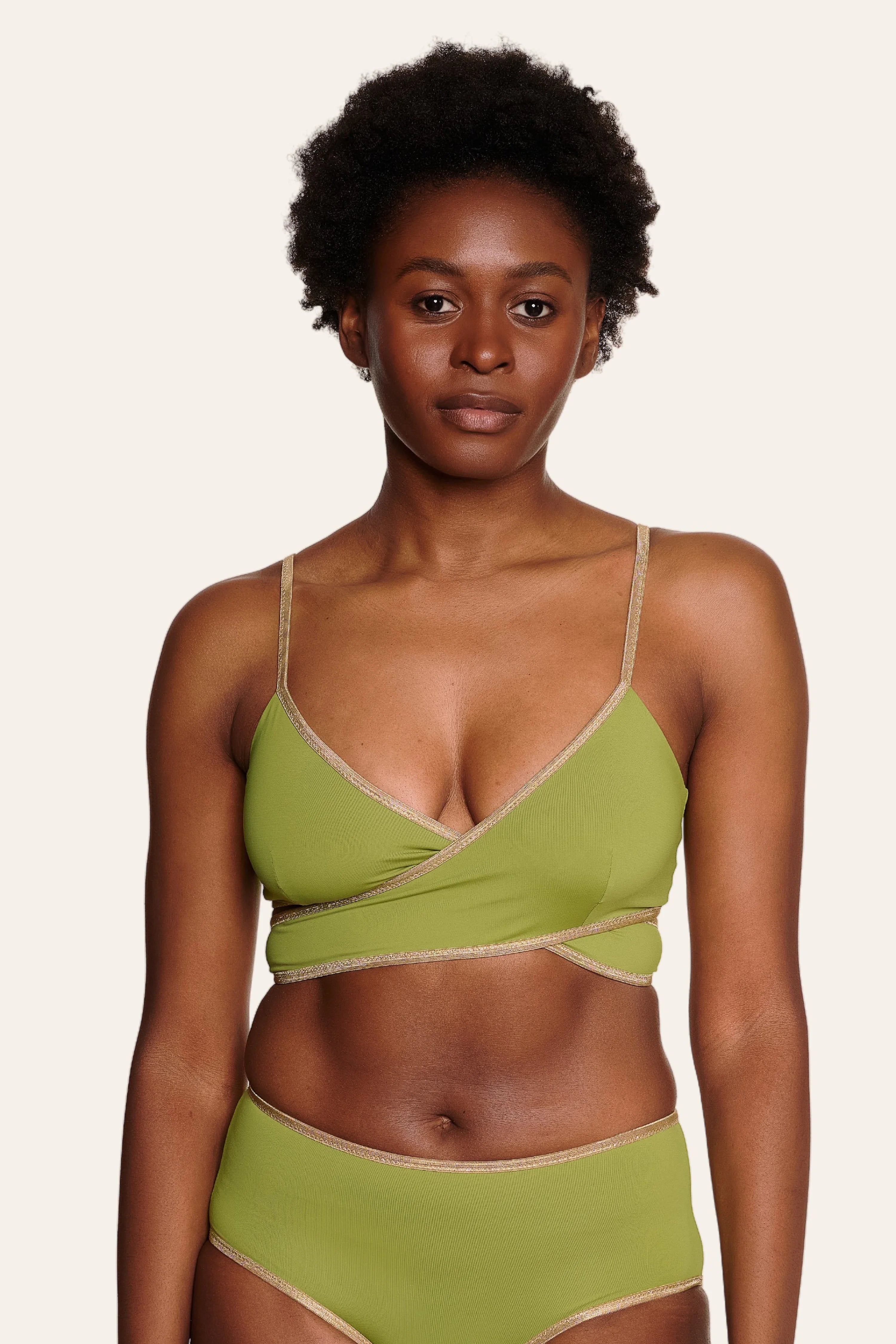 Frau trägt MYMARINI Bikinitop mit V-Ausschnitt und Spaghettiträgern sowie passende Bikinihose in Olivgrün.#color_apple-leaves