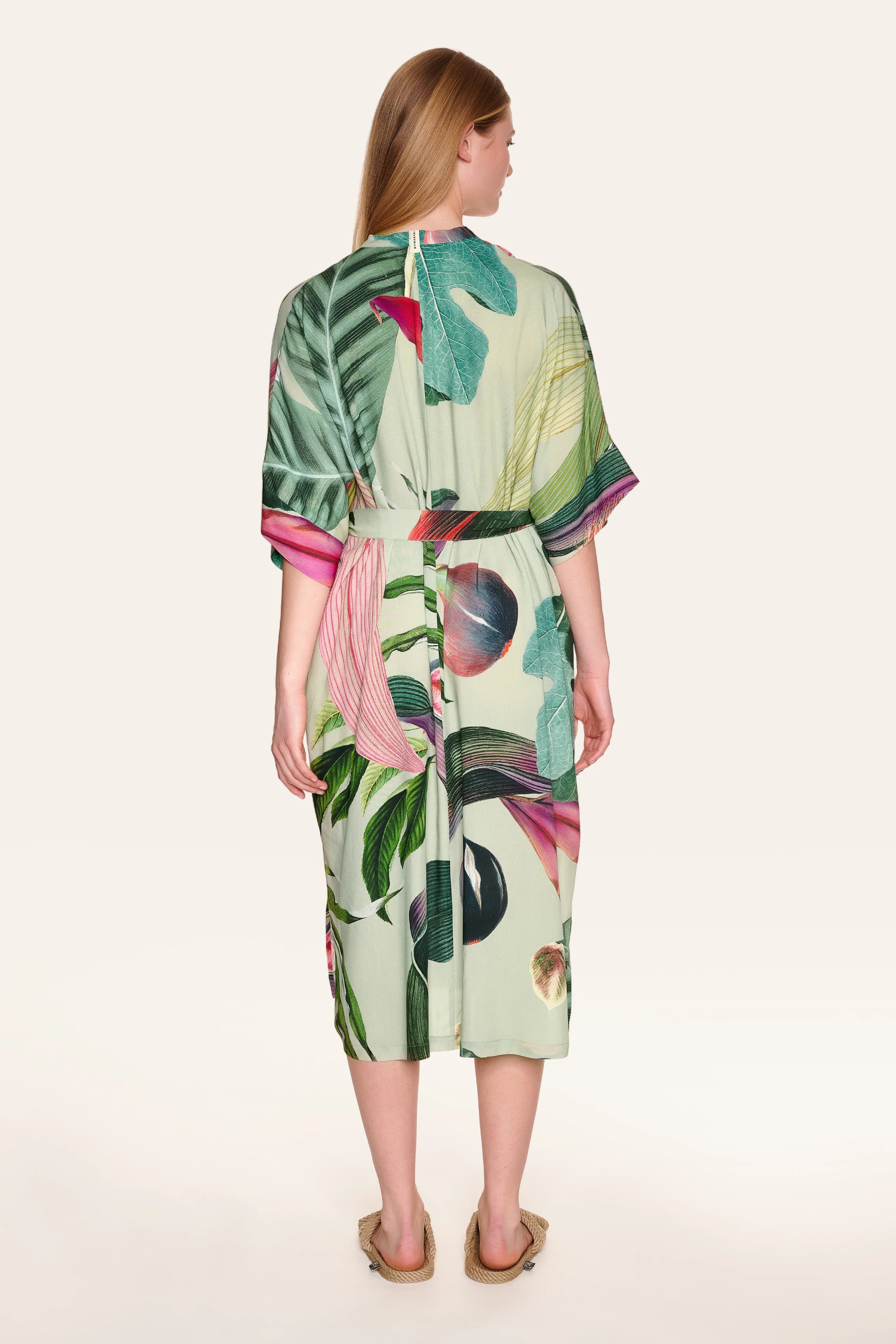 Person von hinten in einem MYMARINI-Kleid mit tropischem Muster und kurzen Ärmeln.#color_tropical-print