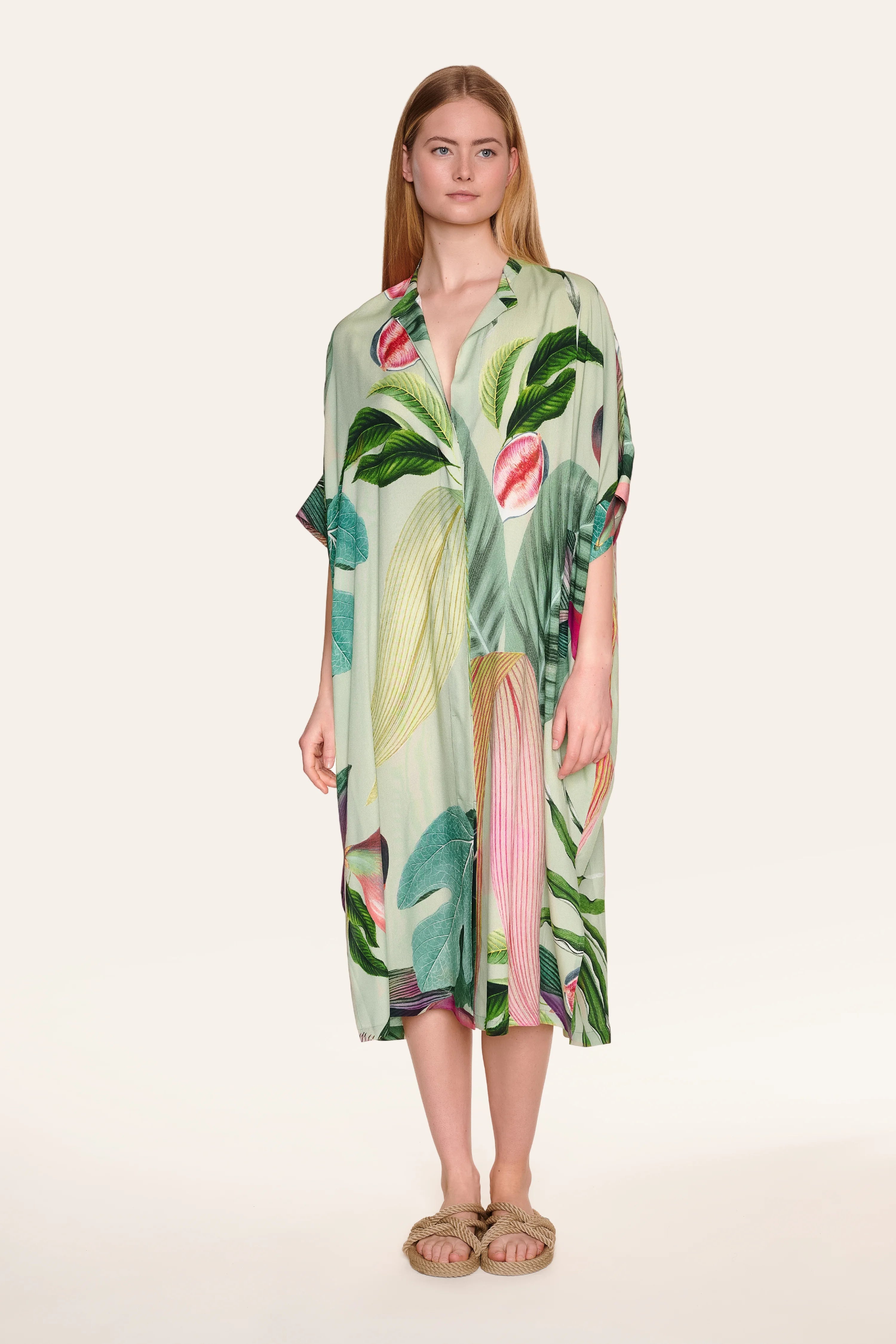 Person trägt ein MYMARINI-Kleid mit tropischem Muster und V-Ausschnitt.#color_tropical-print