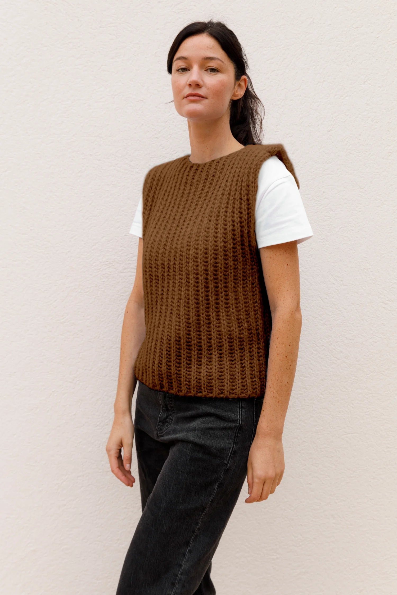 Frau trägt braunes MYMARINI-Top über weißem T-Shirt, vor hellem Hintergrund.#color_camel