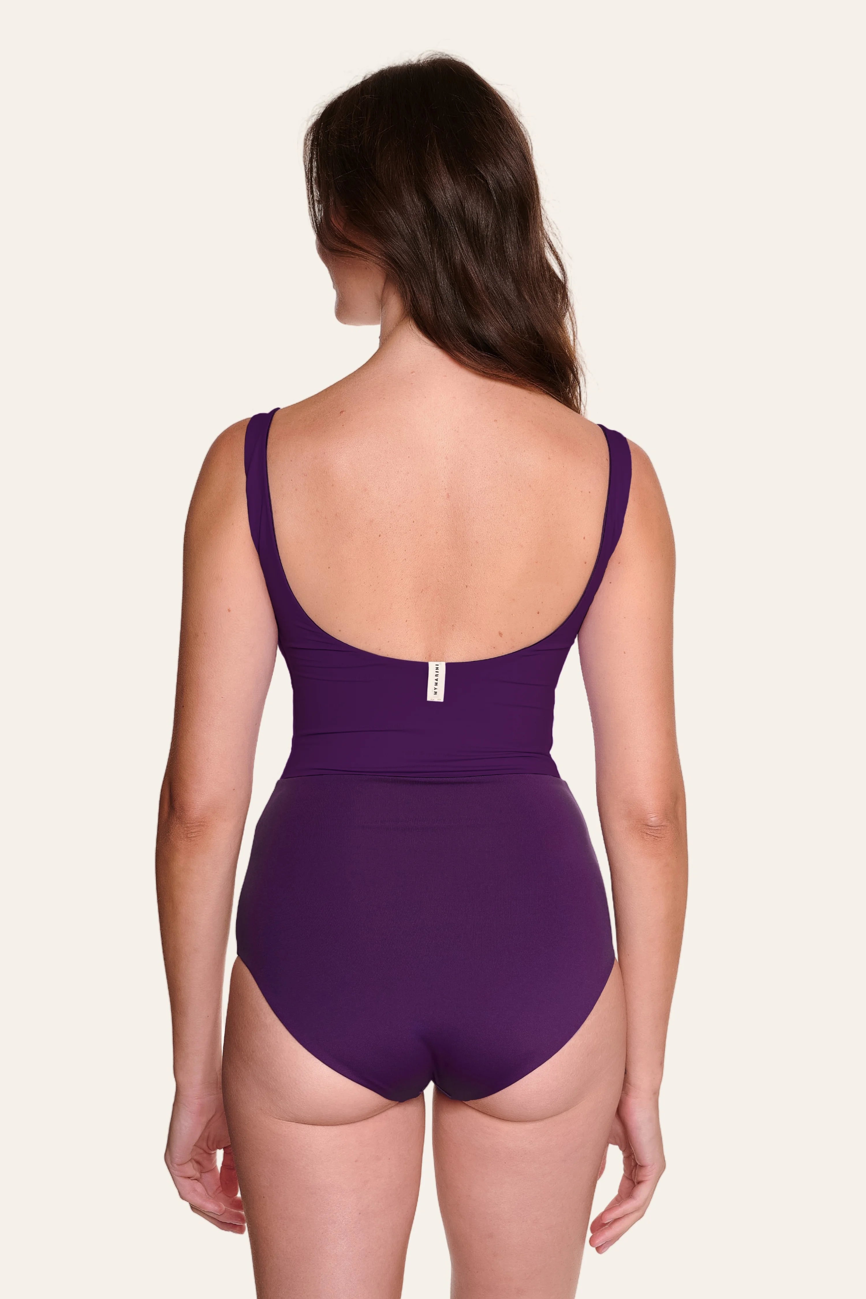 Frau in lila MYMARINI Badeanzug mit tiefem Rückenausschnitt und breiten Trägern, von hinten gezeigt.#color_lavender-plum