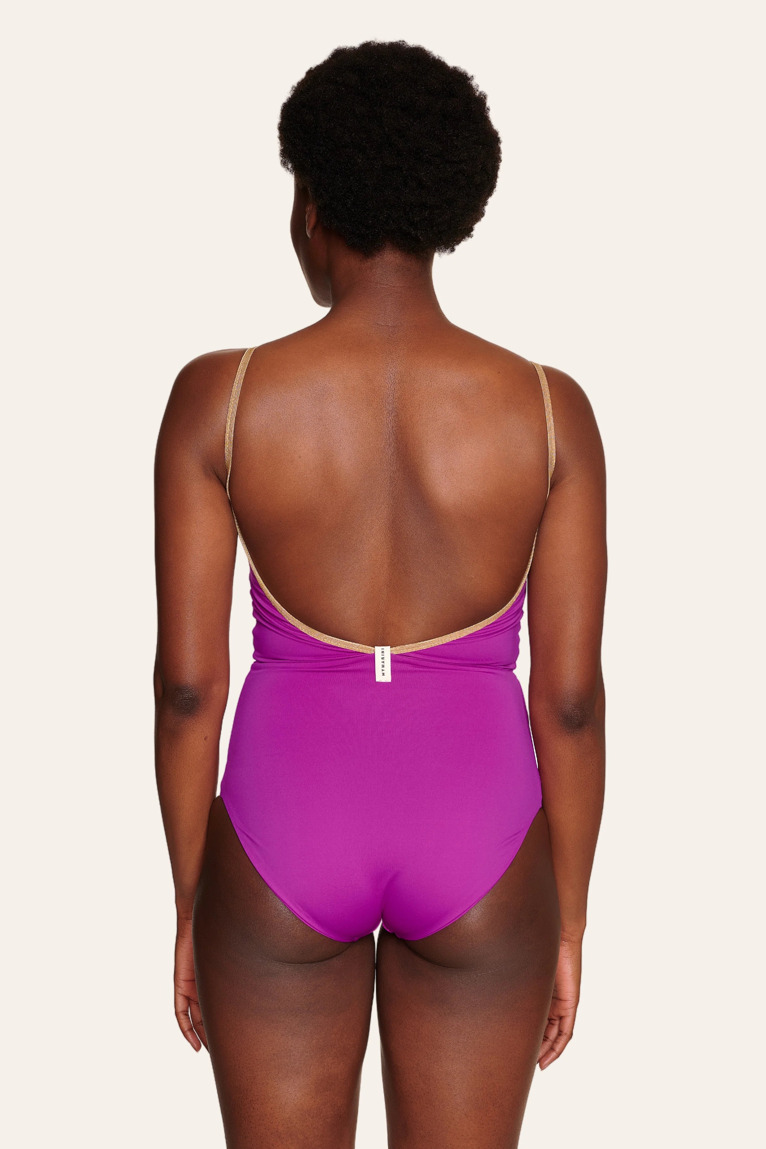 Person trägt einen MYMARINI Badeanzug in Lila mit tiefem Rückenausschnitt und schmalen Trägern.#color_papaya-cassis