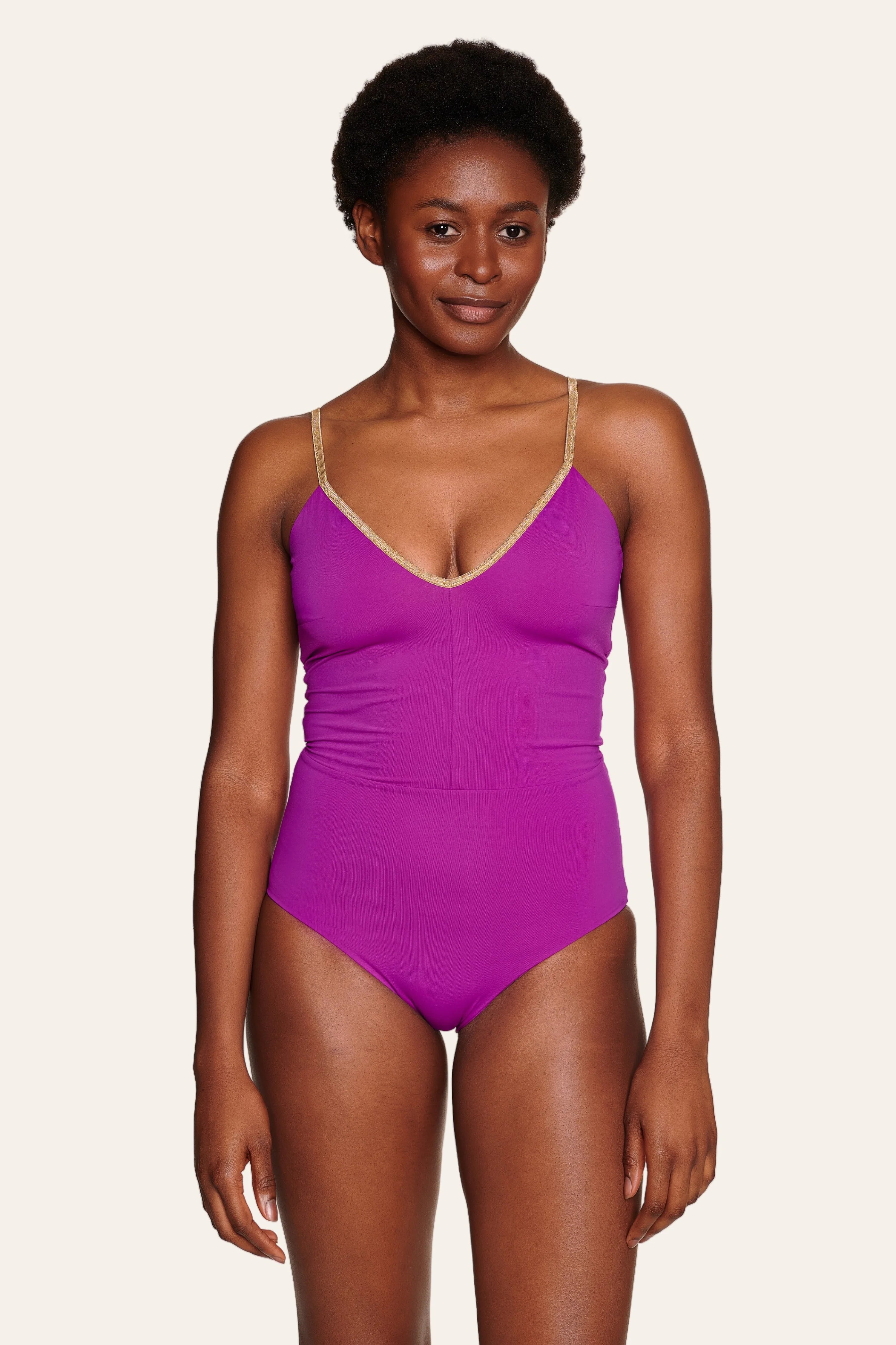 Person trägt einen lila MYMARINI Badeanzug mit V-Ausschnitt und Spaghettiträgern.#color_papaya-cassis