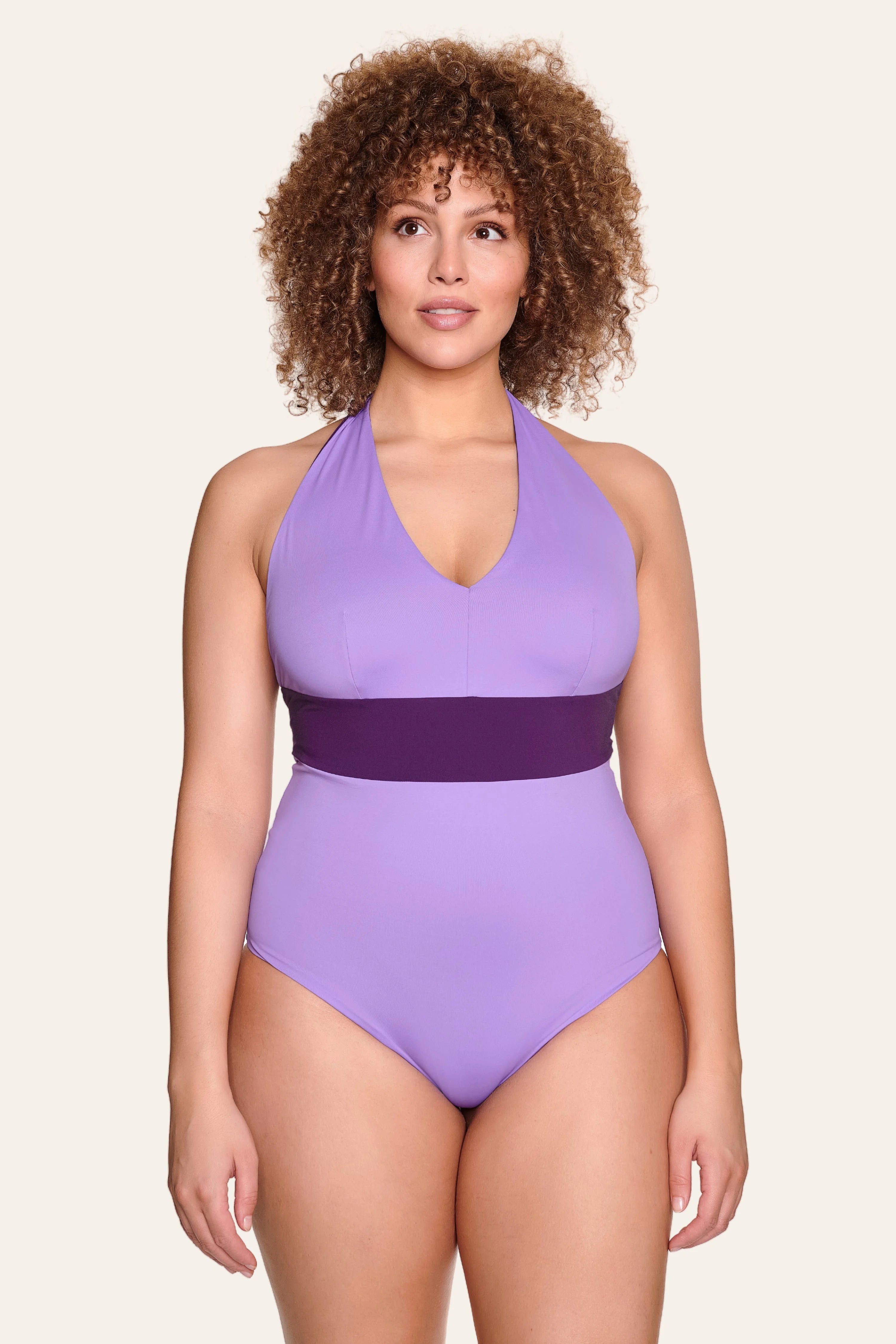 Frau trägt lila MYMARINI Badeanzug mit Neckholder und breitem Bund.#color_lavender-plum