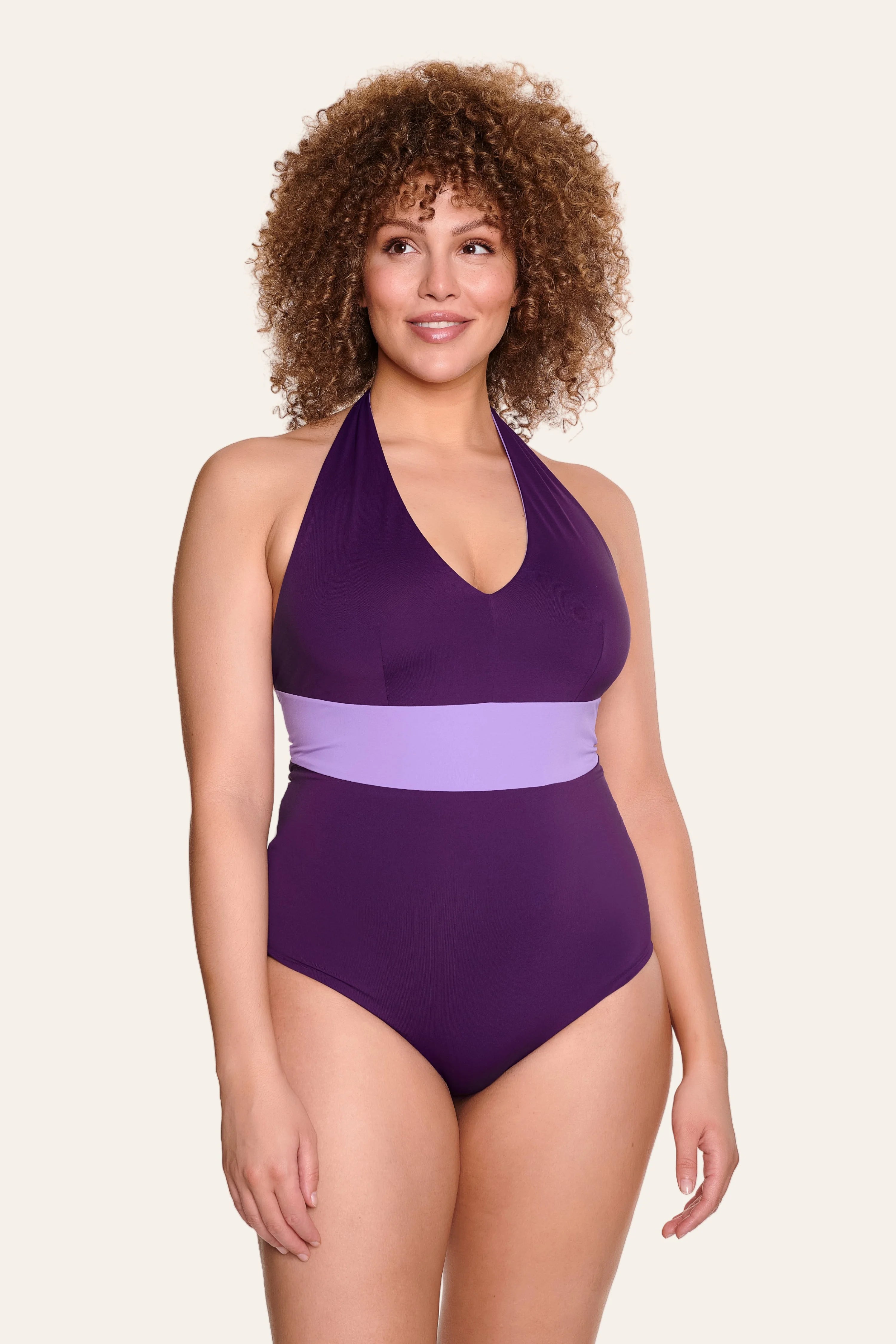 Frau trägt lila MYMARINI One-Piece mit Neckholder und breitem Taillenband.#color_lavender-plum