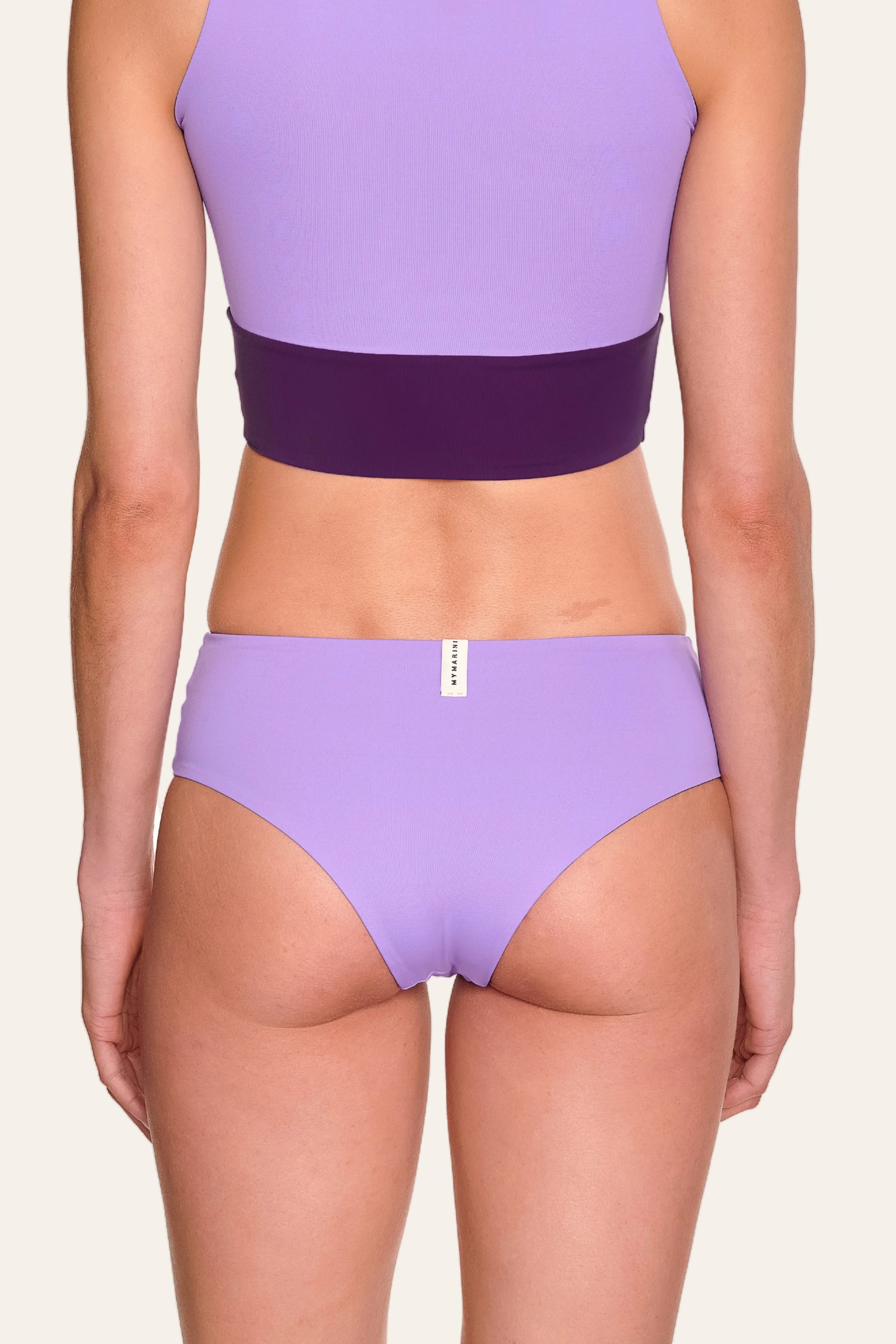 Rückansicht einer Person in lila MYMARINI Bikinihose mit hohem Beinausschnitt und passendem Top.#color_lavender-plum