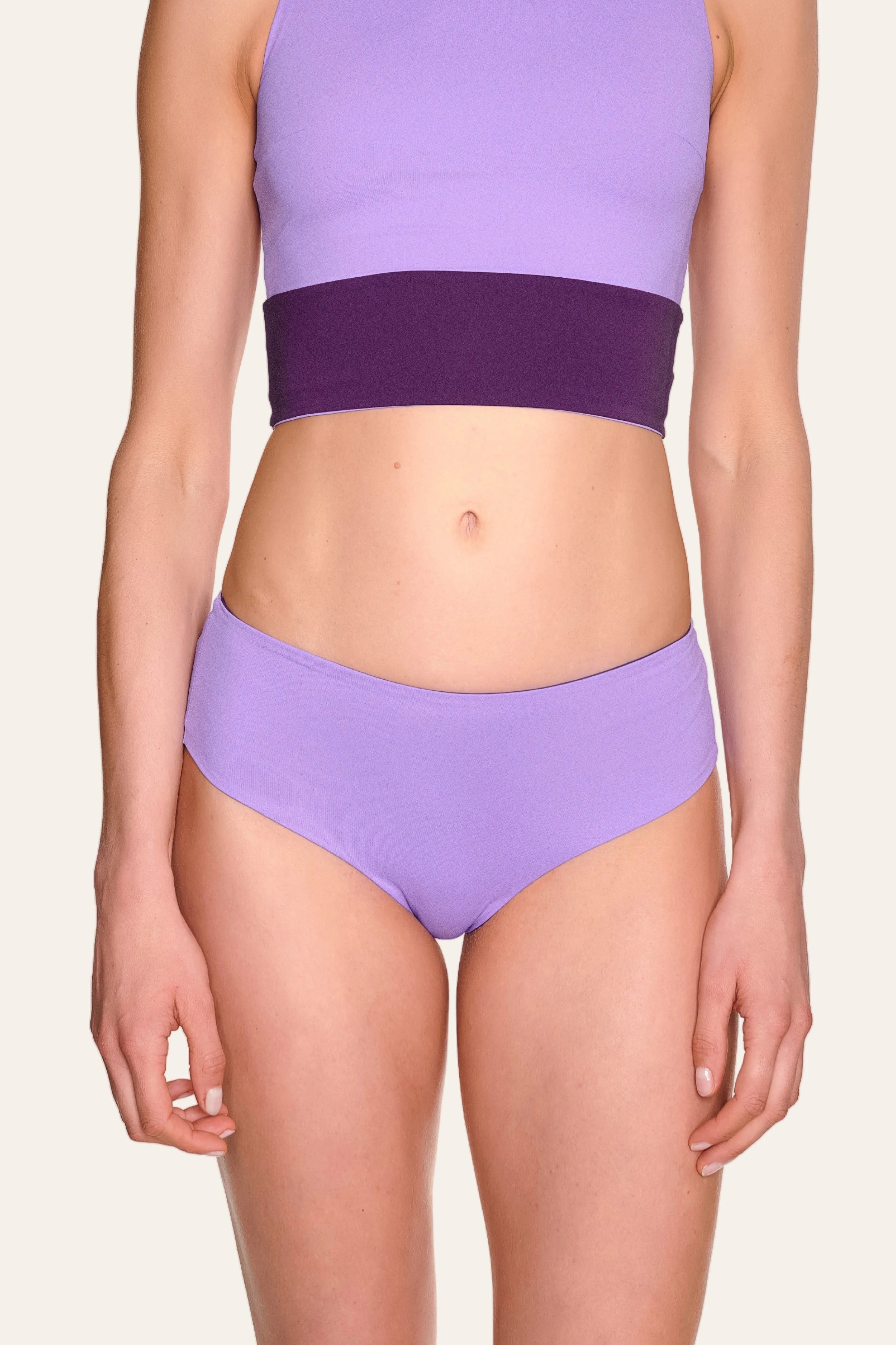 Person trägt MYMARINI Bikinihose in Lila mit hohem Beinausschnitt und passendem Top.#color_lavender-plum