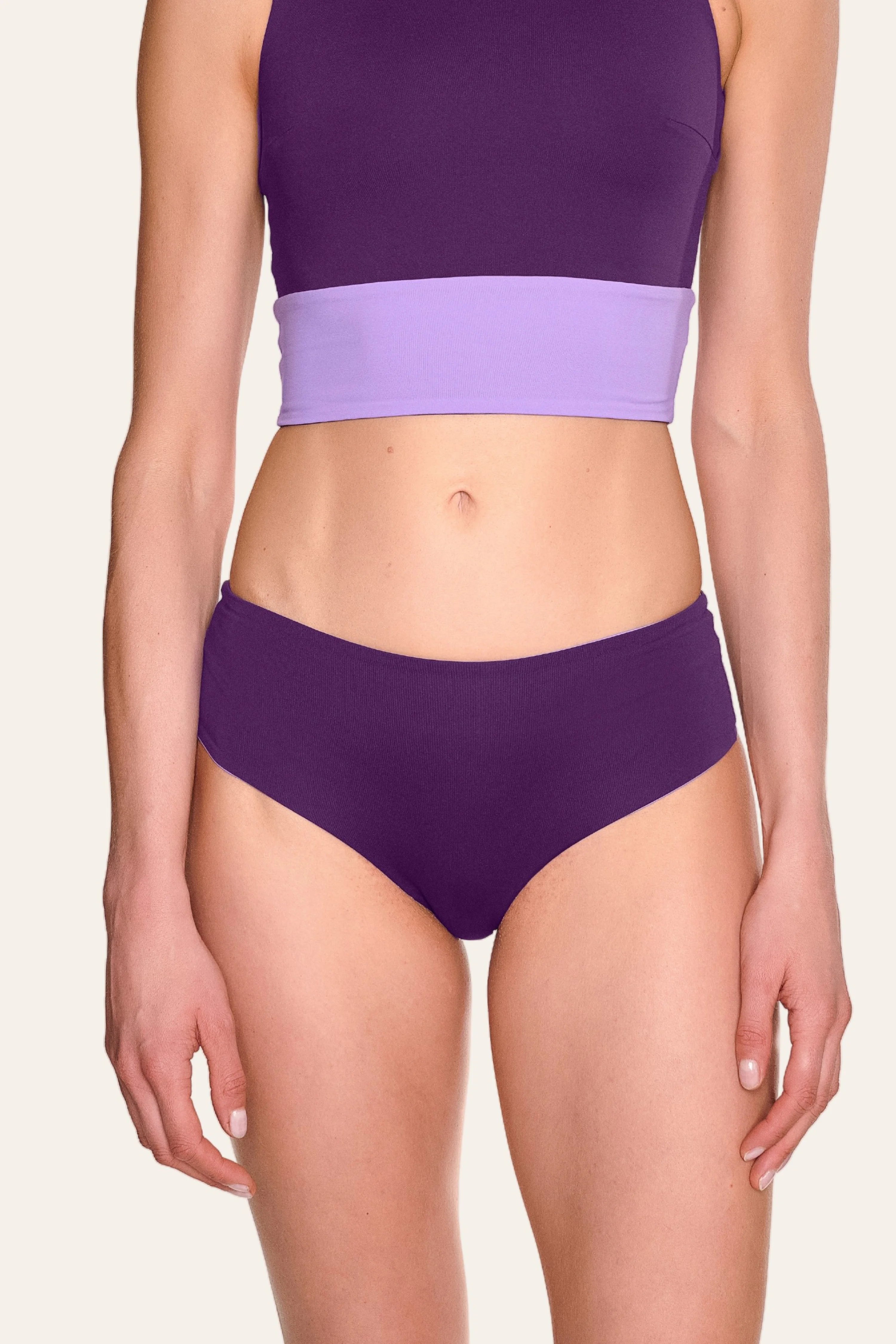 Frau trägt MYMARINI Bikinihose in Lila, hoch geschnitten, mit passendem Top.#color_lavender-plum