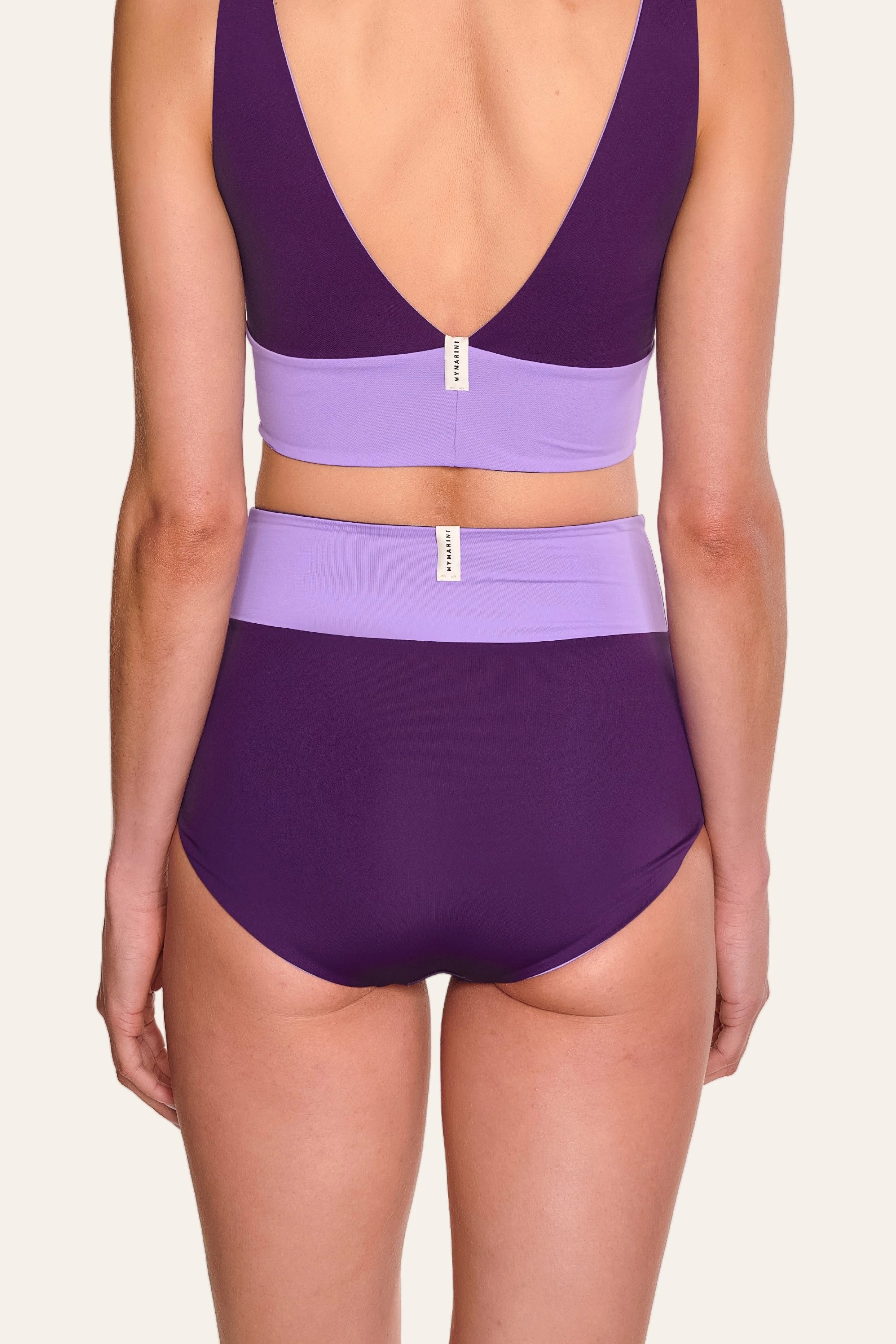 Rückansicht einer Person in einem MYMARINI Bikini mit V-Ausschnitt und High-Waist-Schnitt in Lila und Flieder.#color_lavender-plum