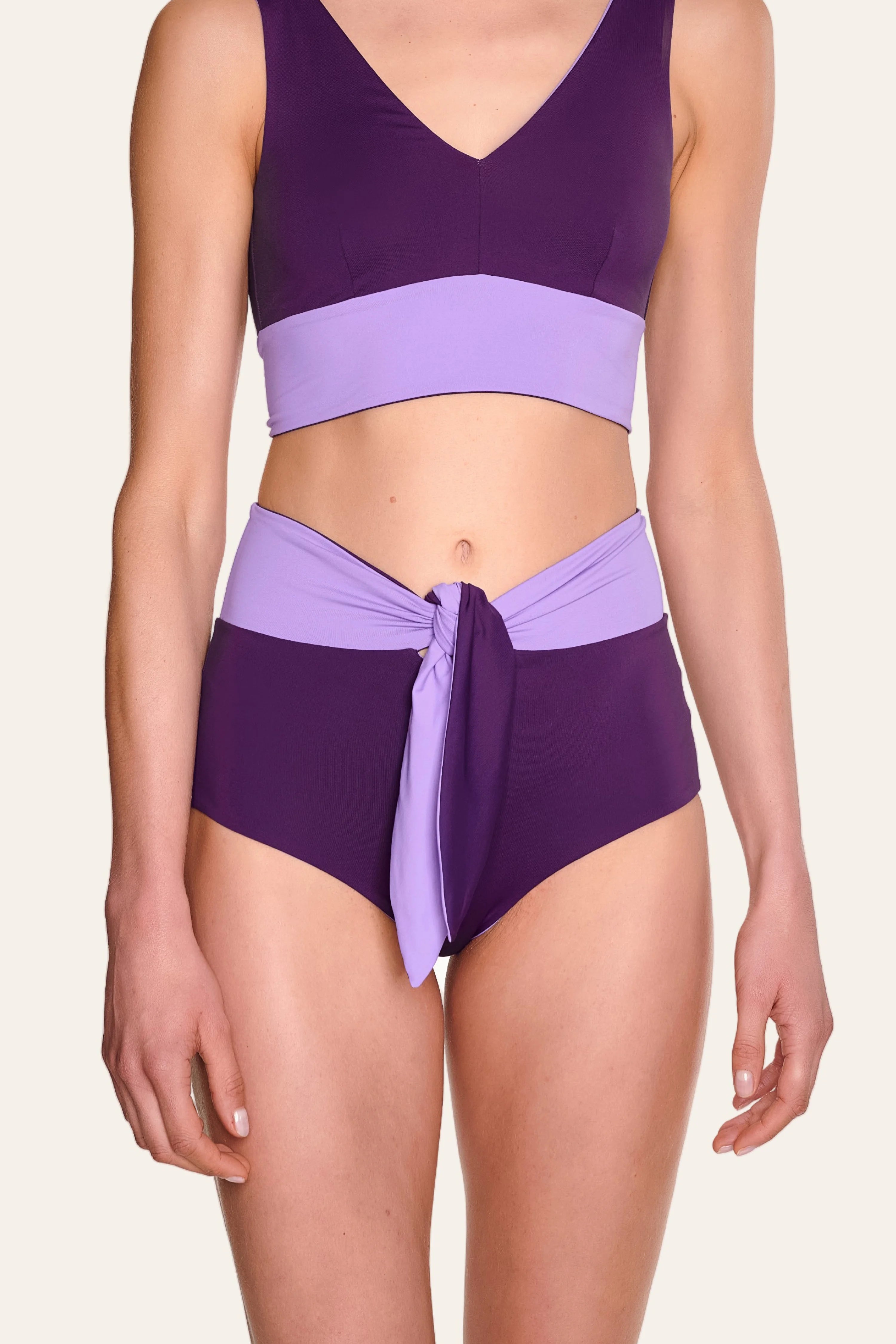 Frau trägt MYMARINI Bikinitop mit V-Ausschnitt und Bikinihose mit hohem Bund in Lila und Flieder.#color_lavender-plum