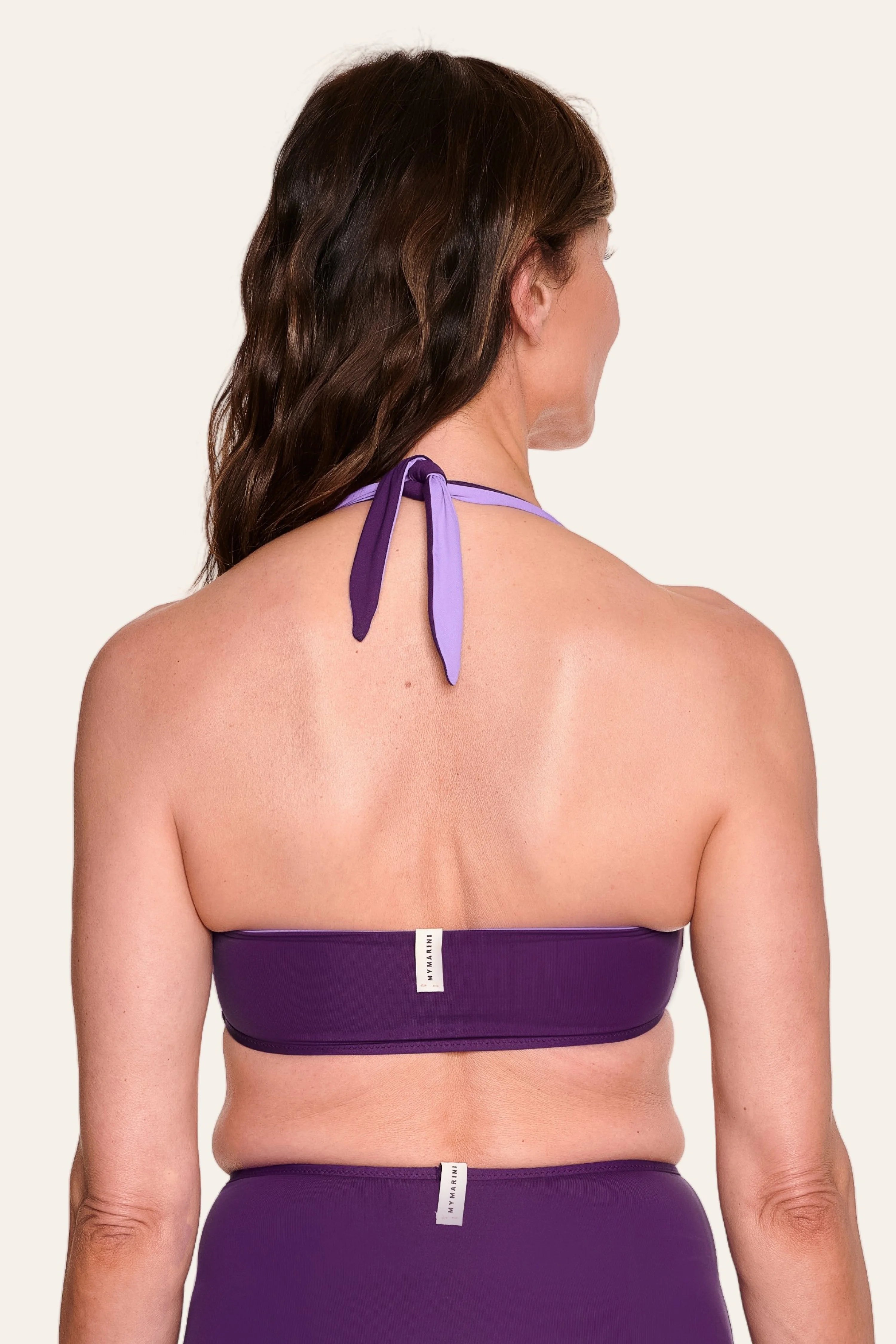 Frau von hinten in lila MYMARINI Bikini mit Neckholder-Top und High-Waist-Hose.#color_lavender-plum