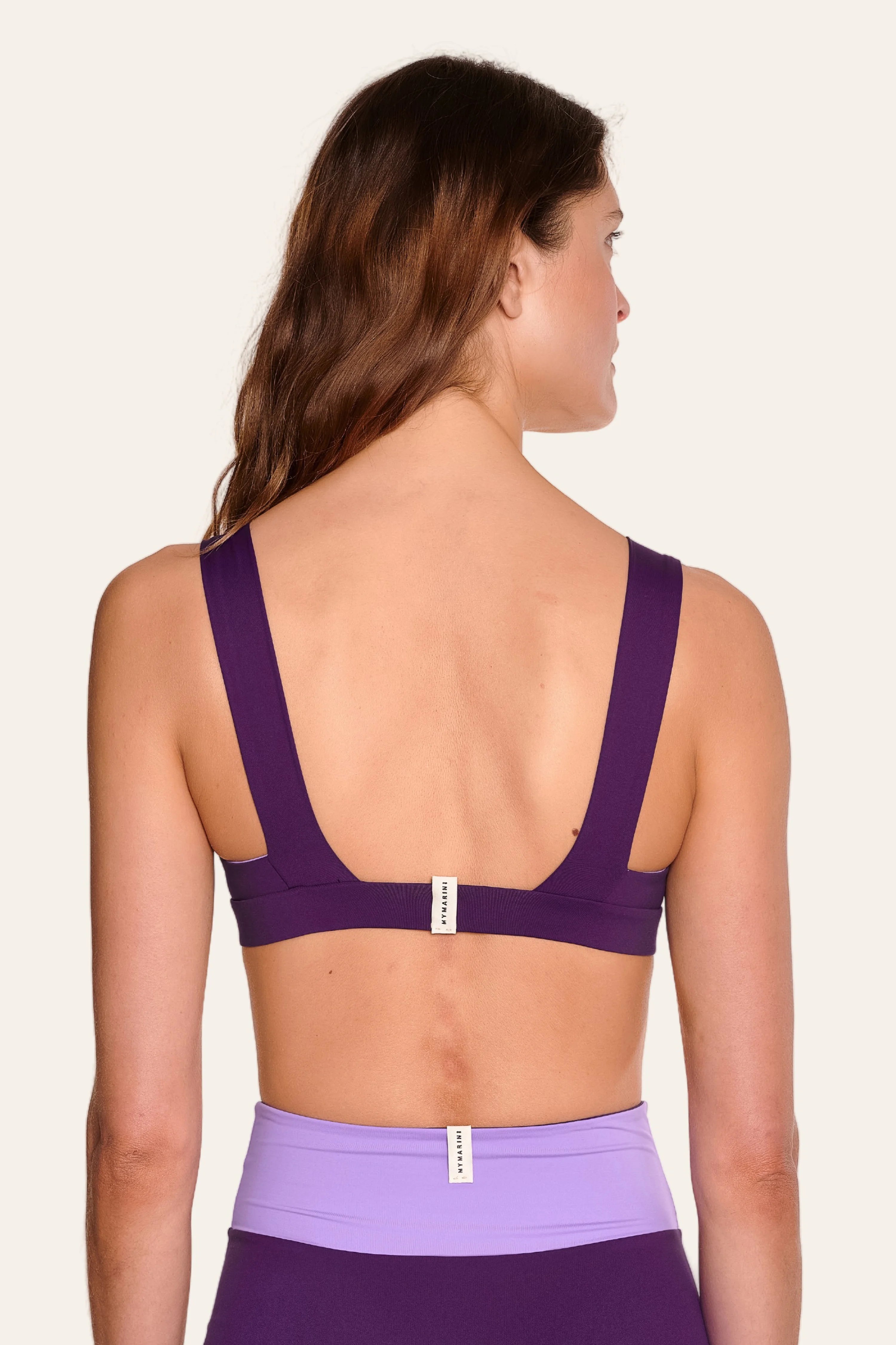Frau in lila MYMARINI Bikinitop mit breiten Trägern und tiefem Rückenausschnitt, dazu passende High-Waist-Bikinihose.#color_lavender-plum